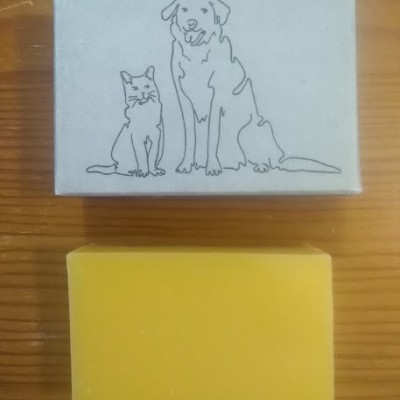 Barra de sabonete amarelo com caixa branca ilustrada com gato e cão