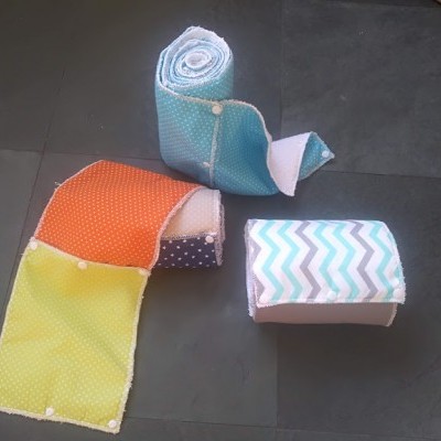 Três mantas de retalhos e padrões variados sobre chão escuro.