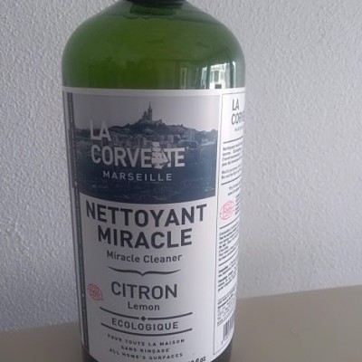 Frasco verde de produto de limpeza com rótulo branco e texto em francês e inglês