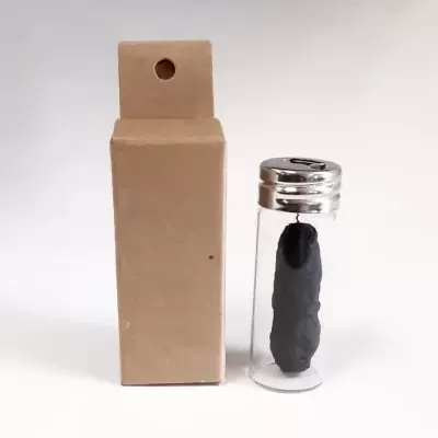 frasco de vidro com objeto preto e caixa de cartão castanha