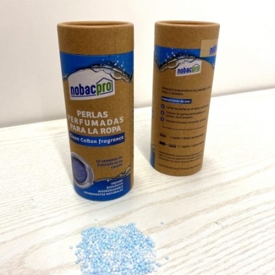 Frascos cilíndricos nobacpro com pérolas perfumadas para roupa e pérolas azuis e brancas sobre mesa de madeira.