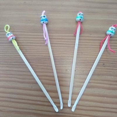 Quatro hastes de madeira com cabeças decorativas coloridas e cordões