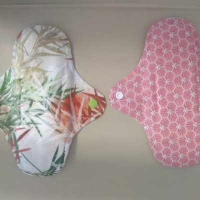 Dois pensos higiénicos reutilizáveis com padrões coloridos e botão pressionador