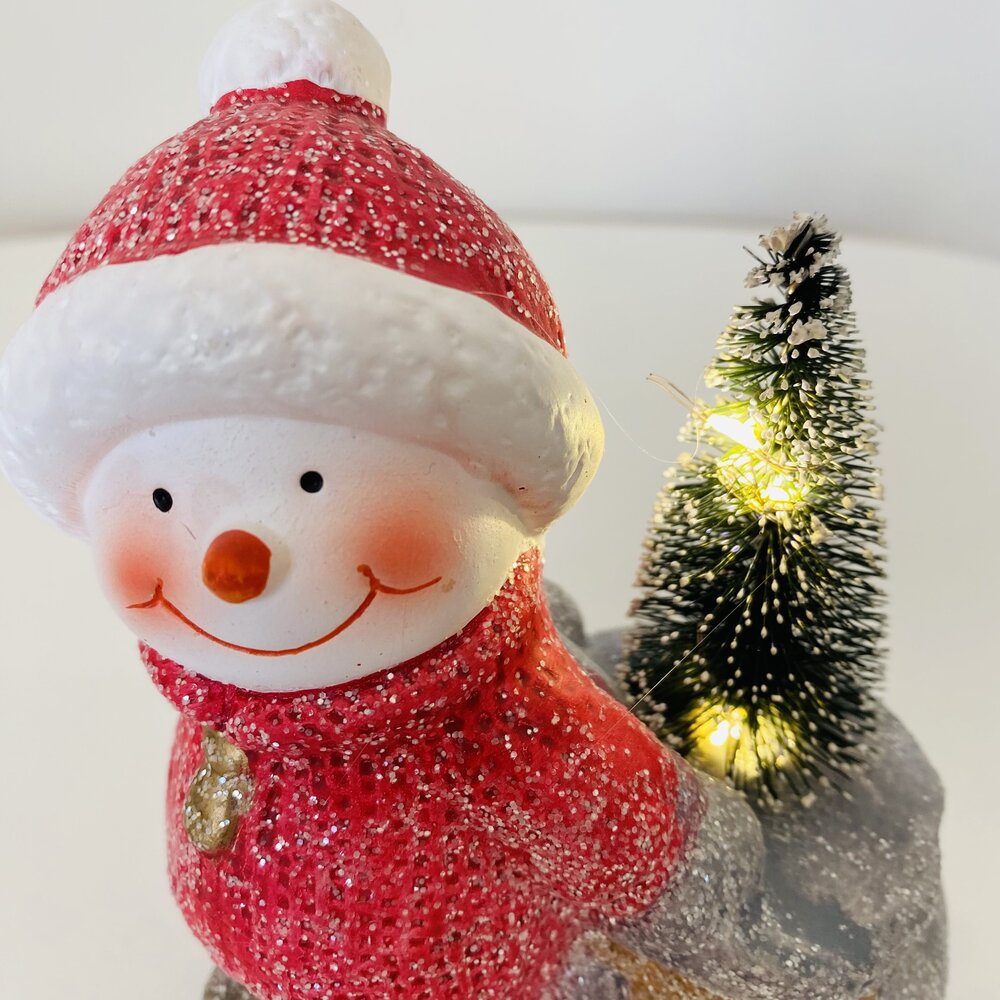 Boneco de neve decorativo vermelho com árvore de Natal verde iluminada