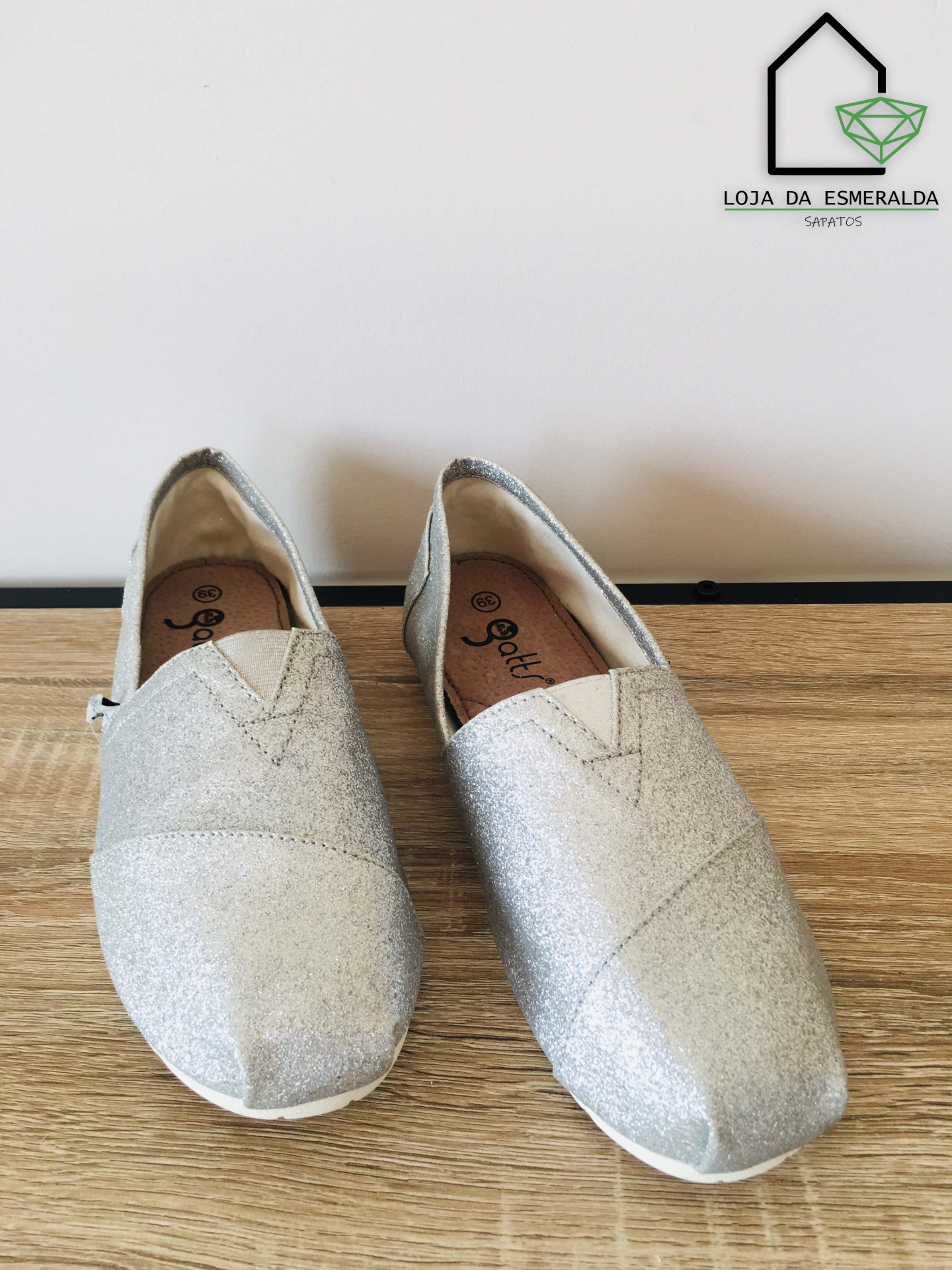 Sapatos femininos slip-on prateados brilhantes sobre superfície de madeira