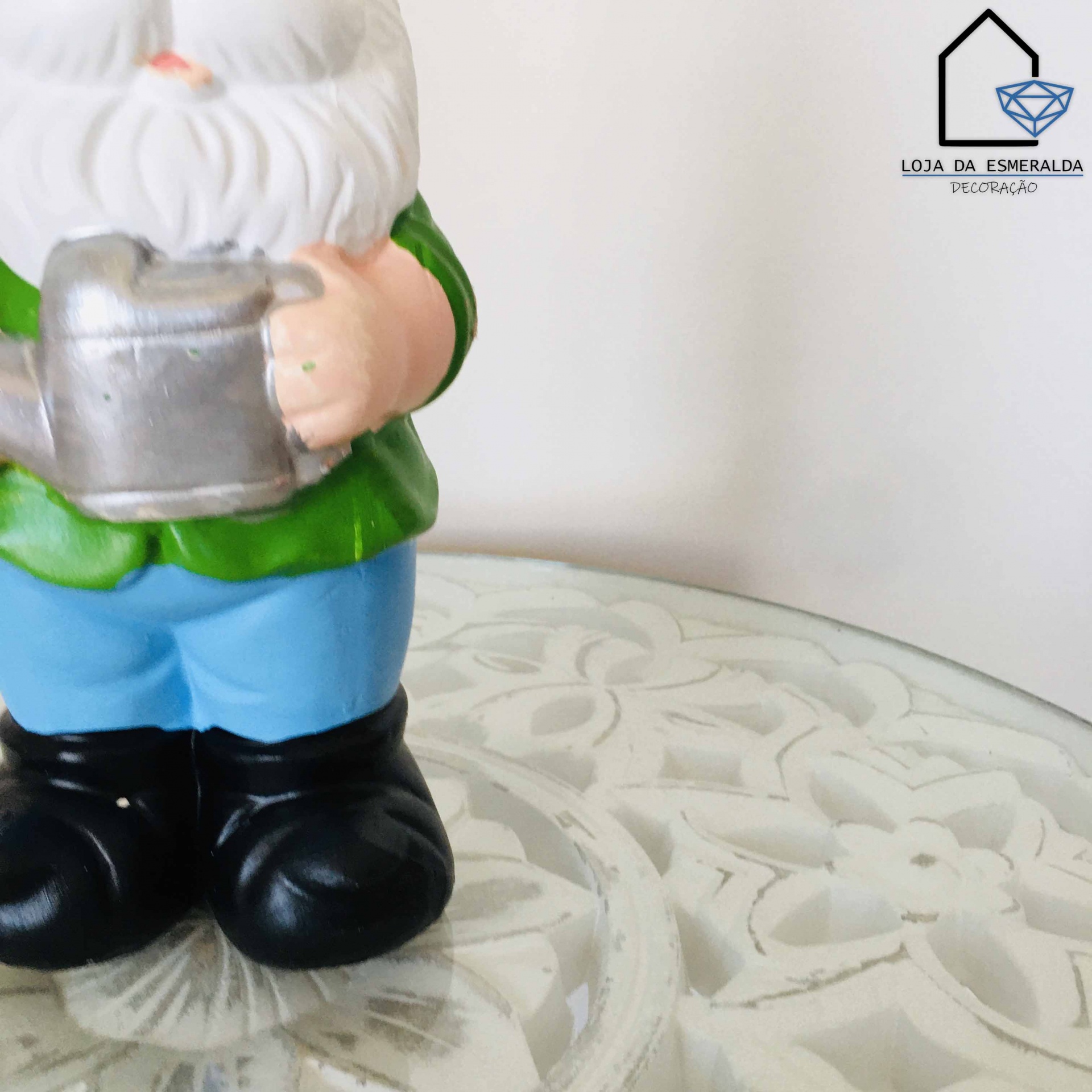Gnomo decorativo com regador numa superfície branca decorada
