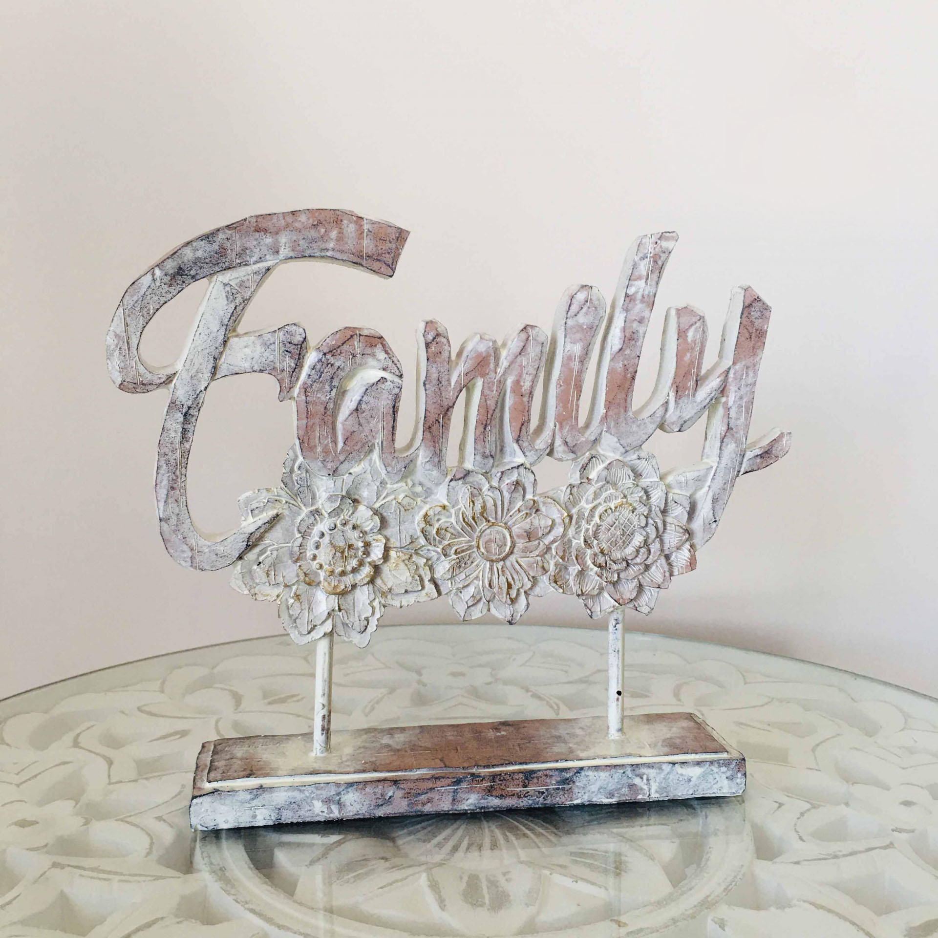 Escultura decorativa de madeira com palavra 'Family' e flores em relevo.