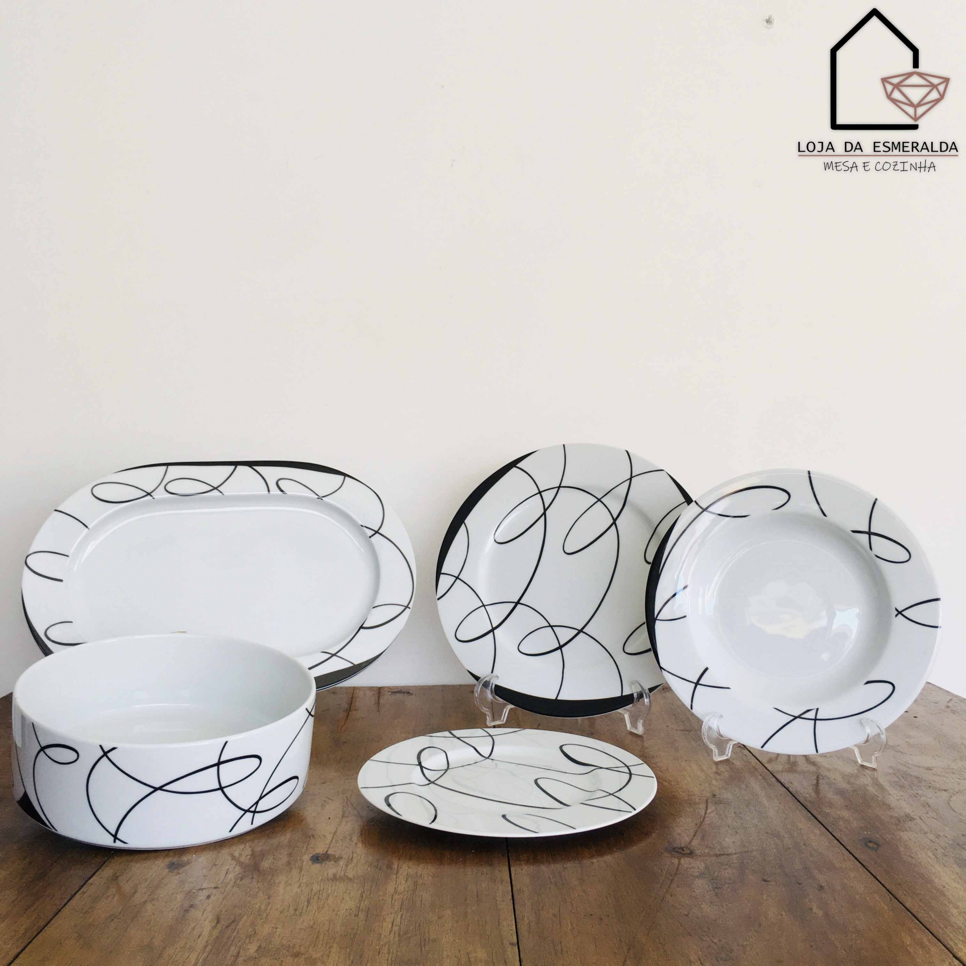 Conjunto de loiça branca com padrão de linhas pretas e logótipo da loja no canto superior direito