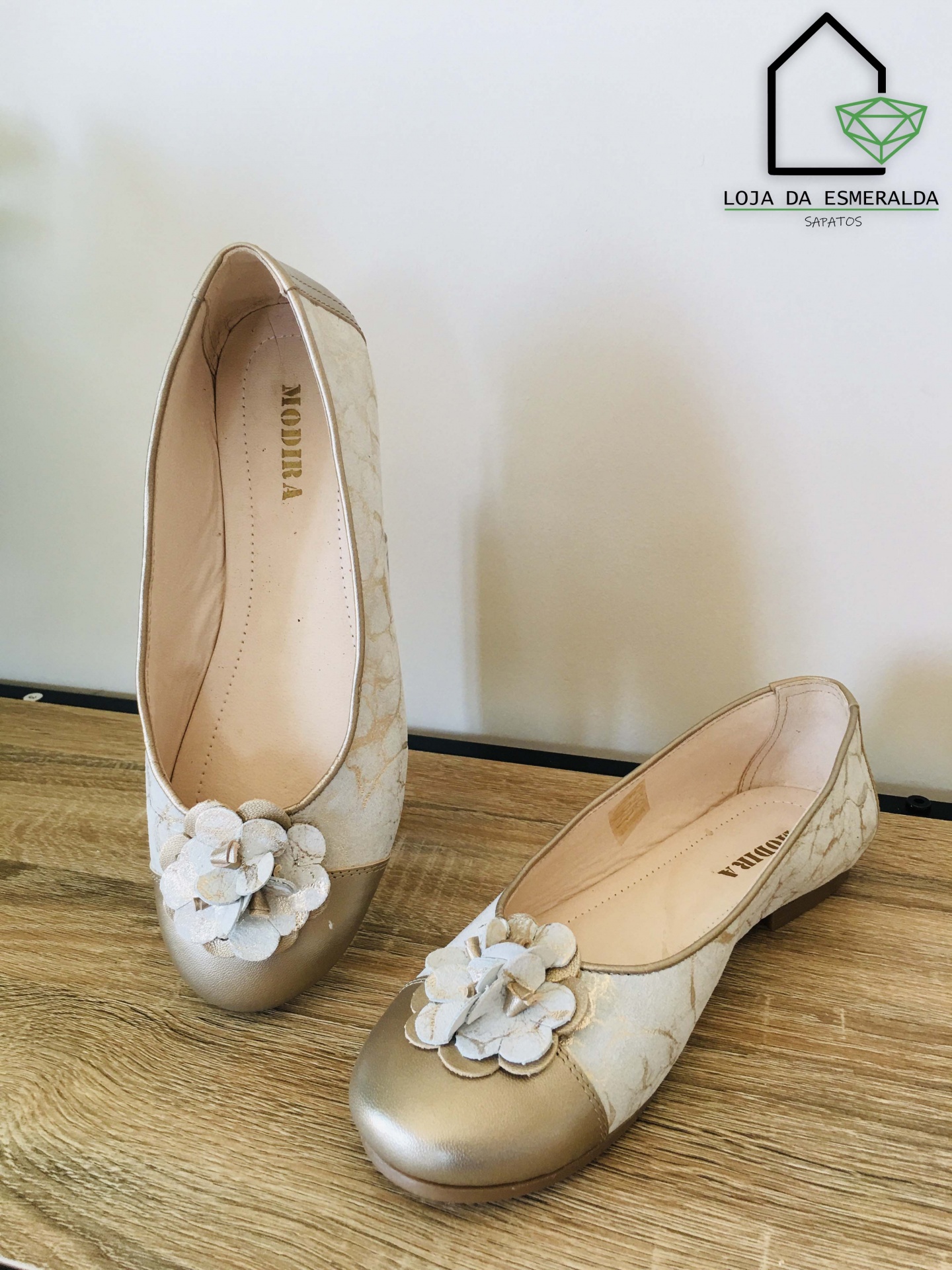 Sapatilha feminina bege e dourada com flor decorativa e padrão floral subtil.