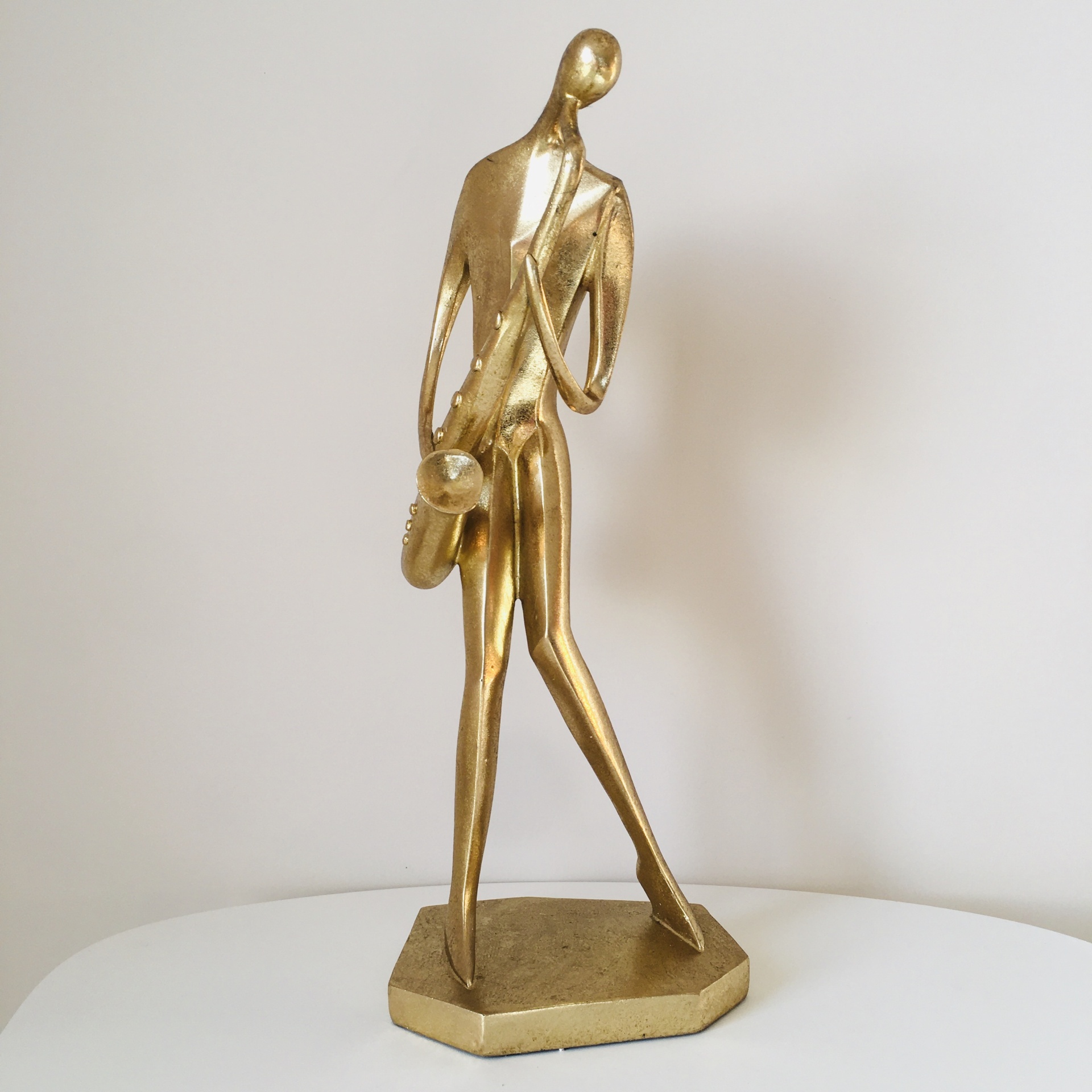 Estatueta dourada abstrata de figura humana com saxofone