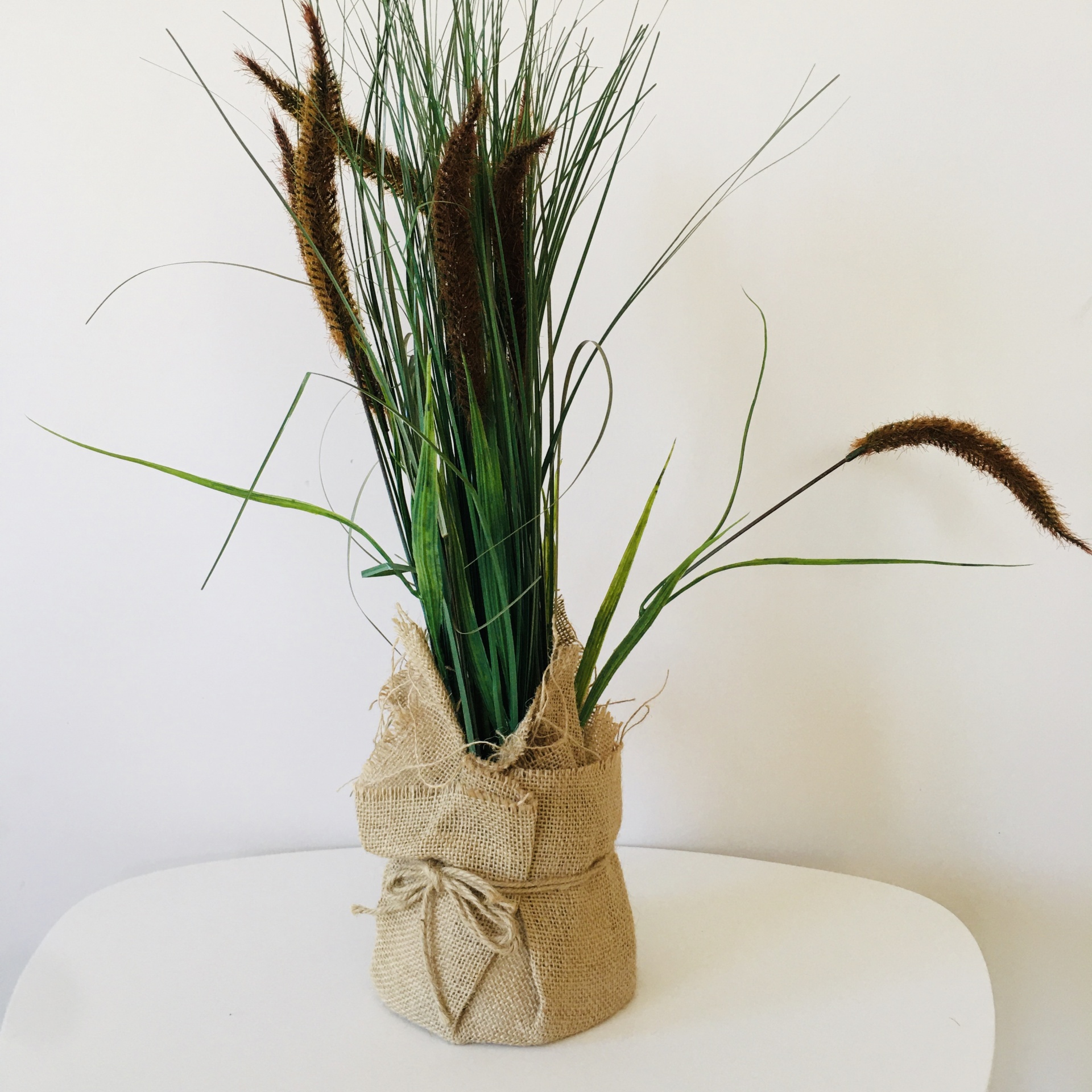 Arranjo de plantas artificiais em juta sobre superfície branca