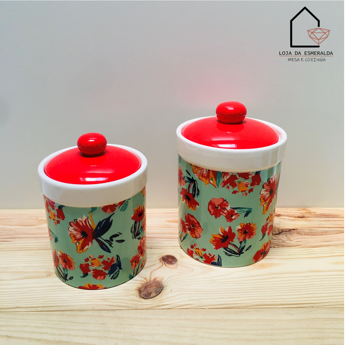 Dois frascos de cerâmica com tampa vermelha e padrão floral sobre mesa de madeira