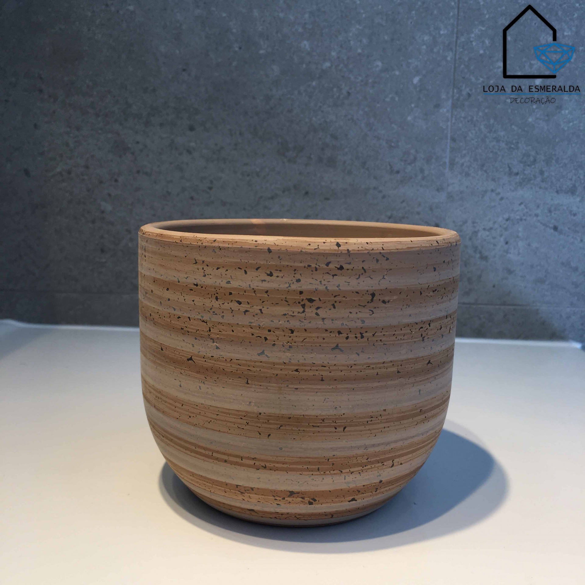 vaso redondo de cerâmica com padrão listrado castanho sobre superfície branca