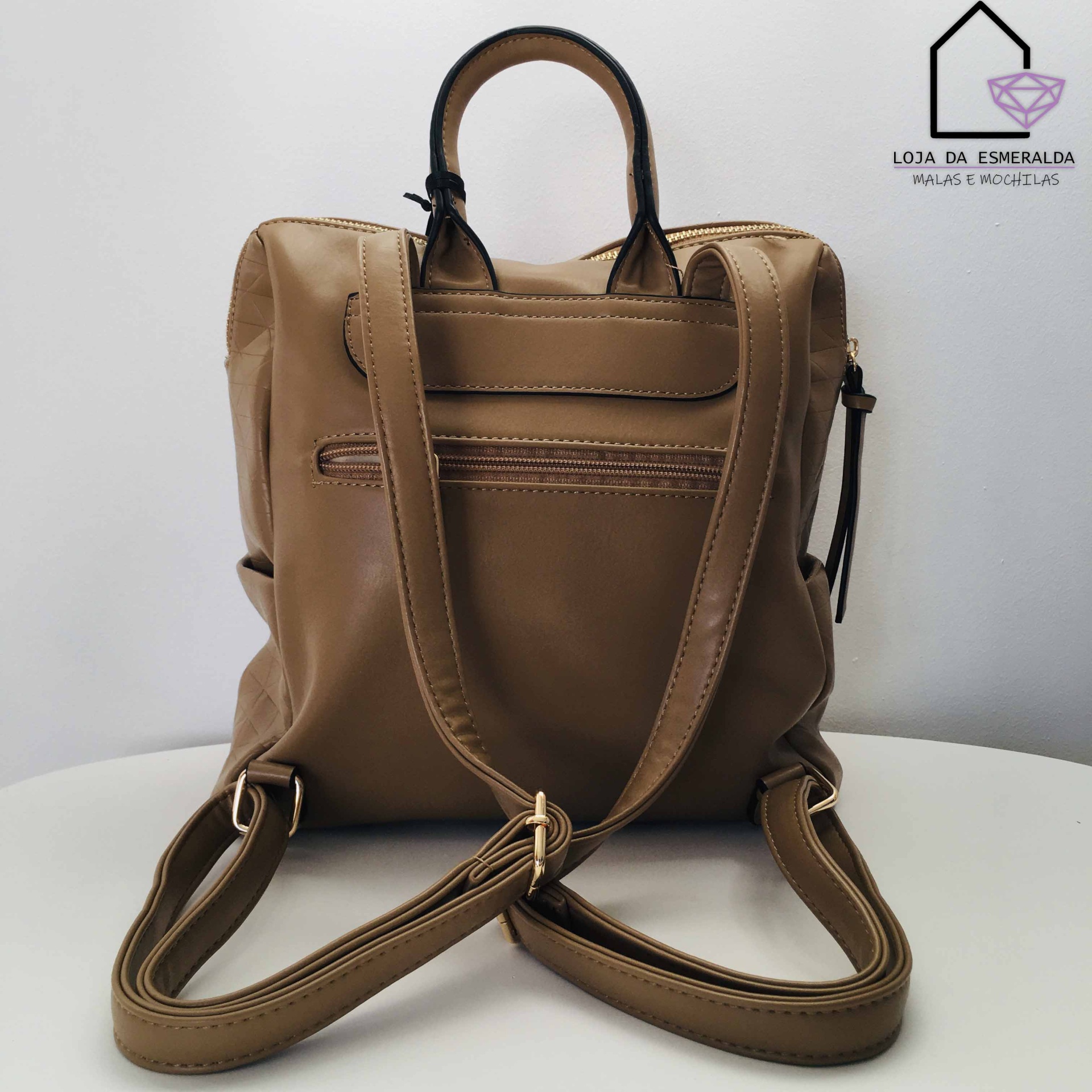 Mochila em couro castanho com alças ajustáveis e logótipo da loja na parede