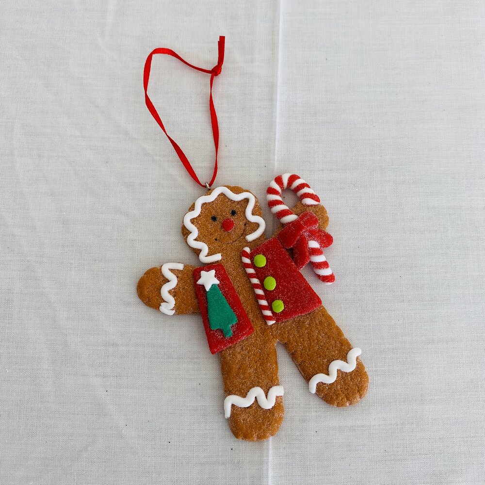 Boneco de gengibre em tecido colorido com bastão de doces e fita vermelha.