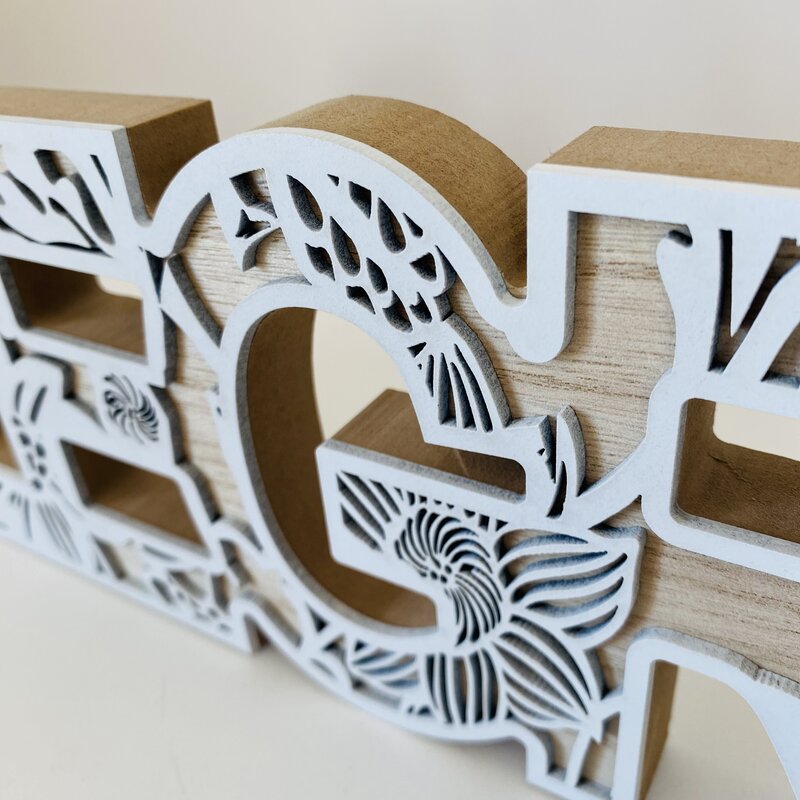 Letra decorativa em madeira com detalhes brancos recortados