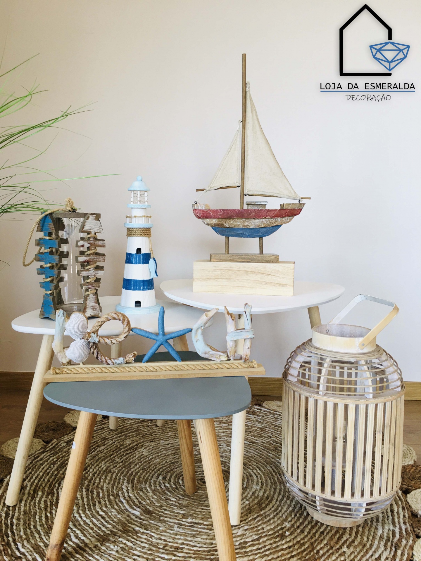 Decoração náutica com barco de vela, farol e lanterna de madeira em mesas sobre tapete rústico