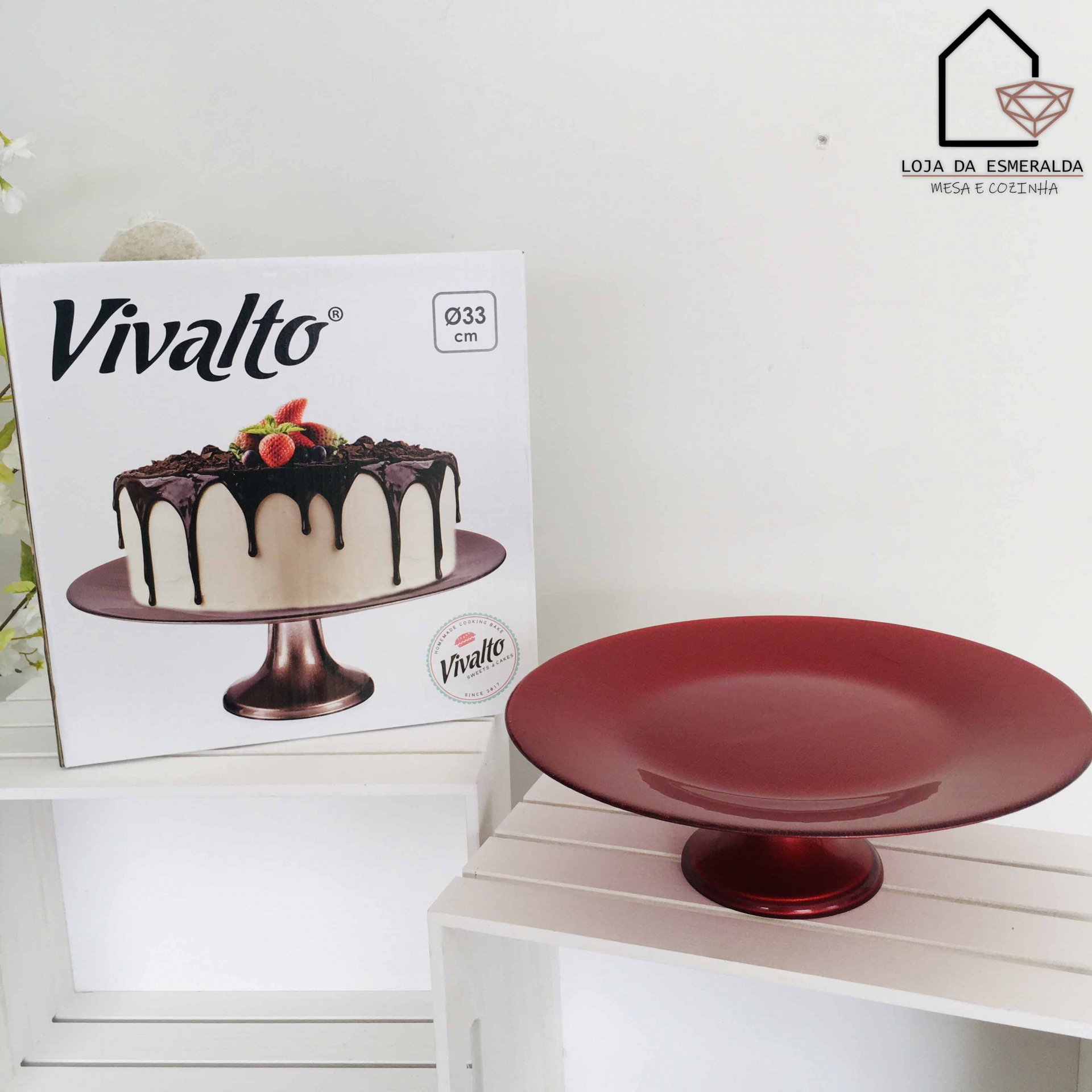 Prato para bolo vermelho em metal com embalagem ao lado mostrando bolo decorado
