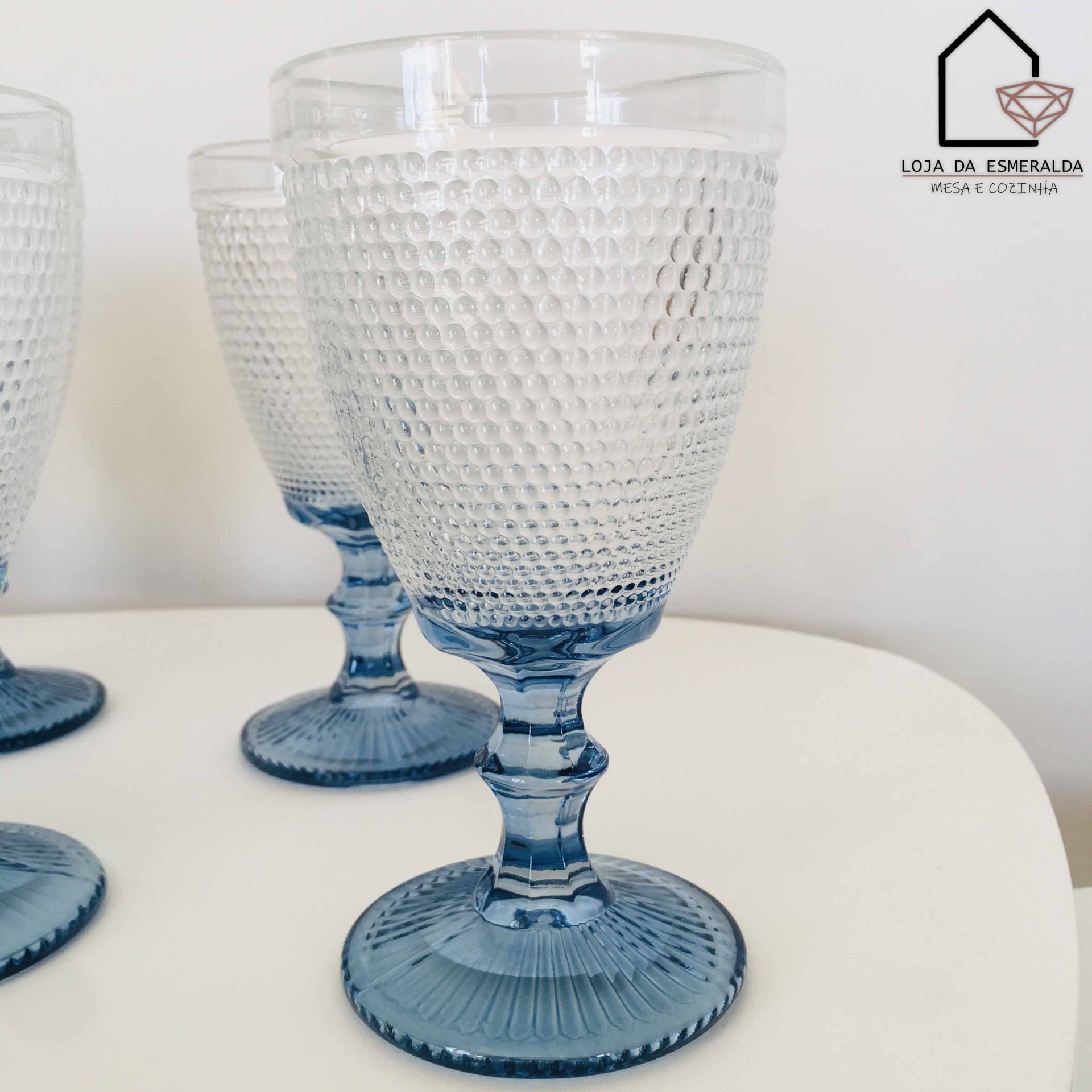 Conjunto de copos de vidro com padrão de bolhas e base azul sobre mesa branca