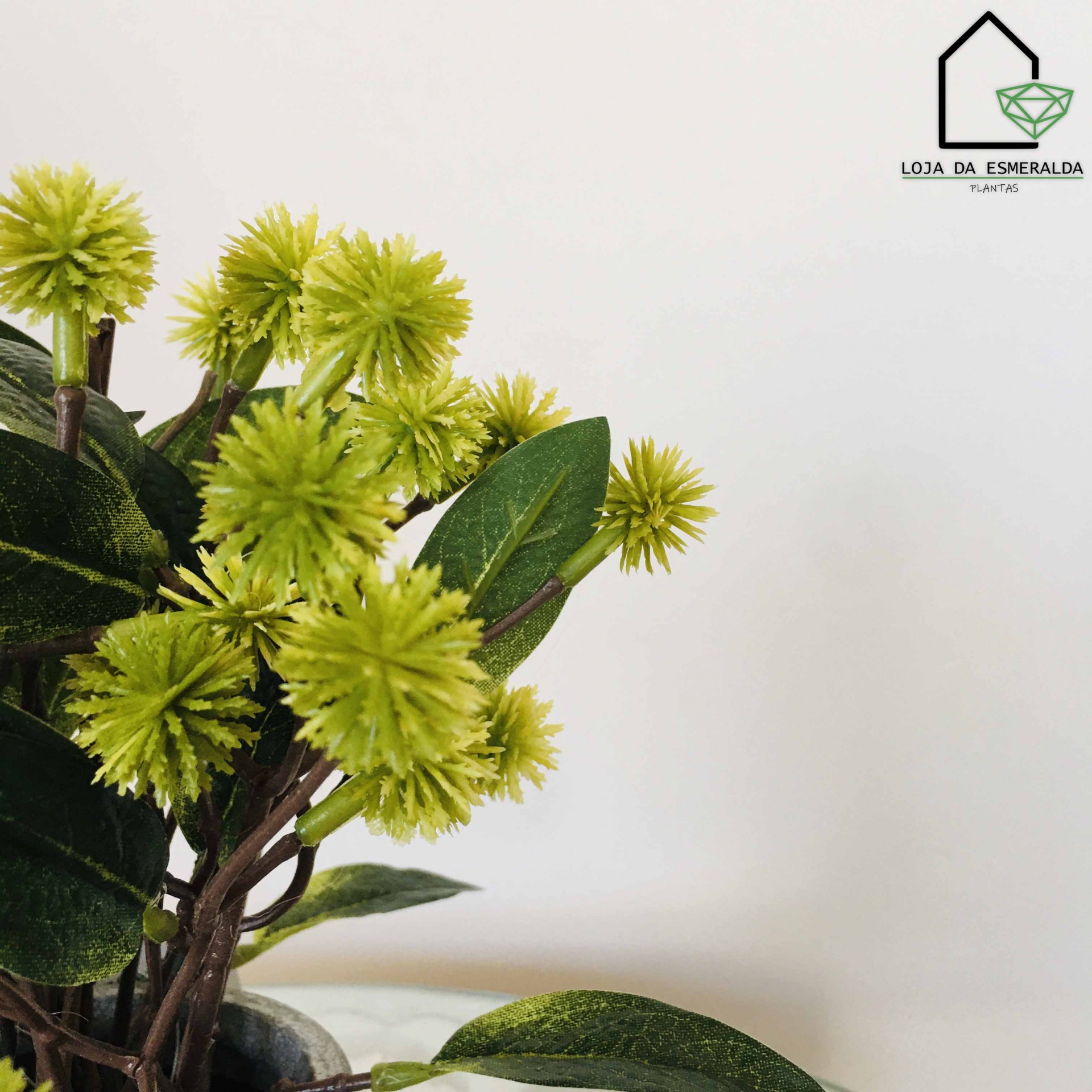 Vaso com flores artificiais verdes e logo LOJA DA ESMERALDA TUIATIS