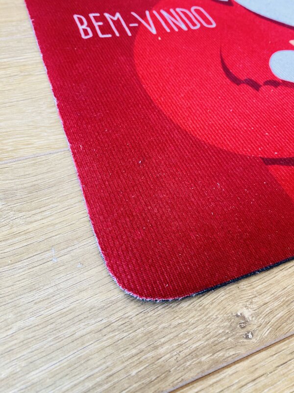 Tapete vermelho com a palavra BEM-VINDO em branco, sobre chão de madeira clara