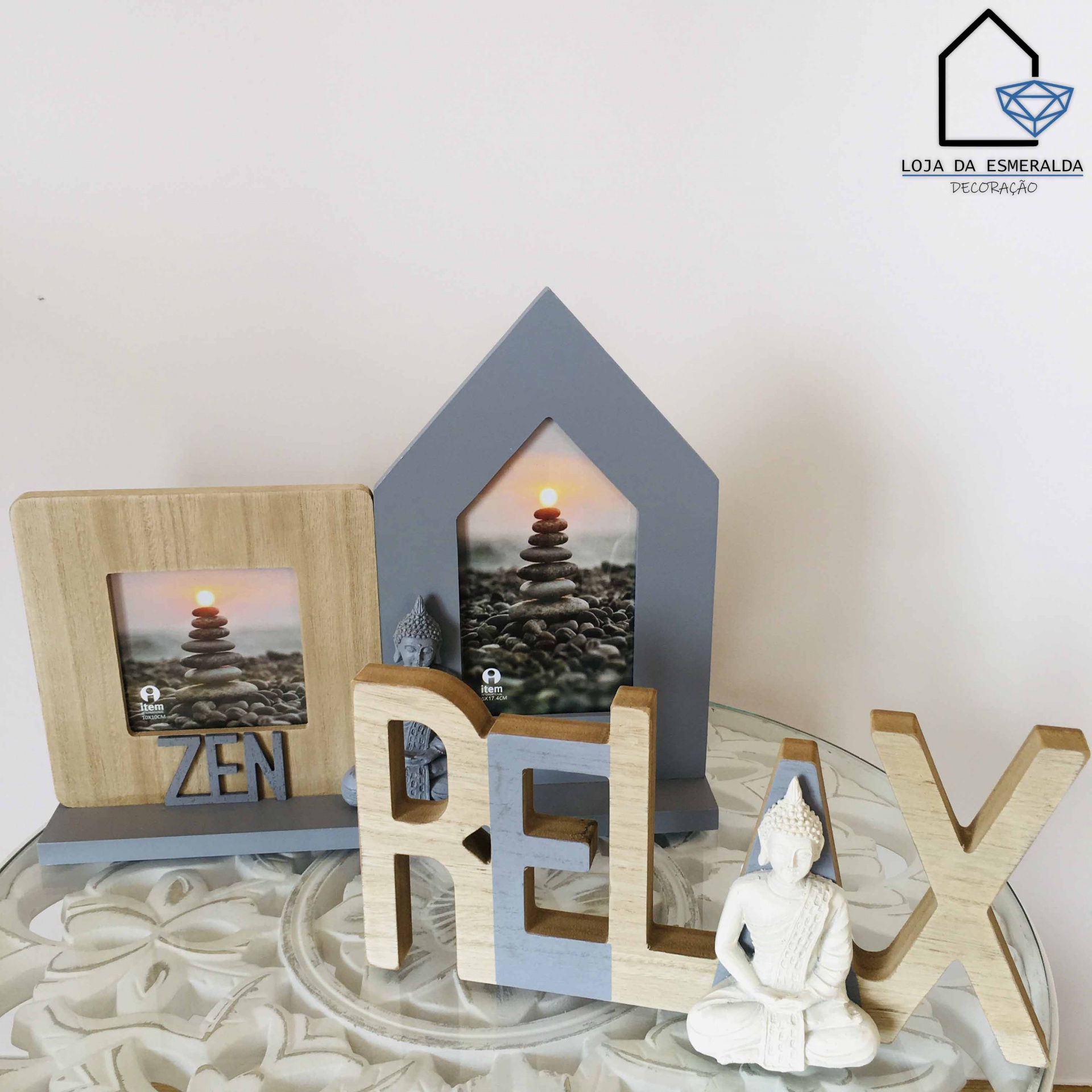 Conjunto decorativo com quadros, palavras em madeira e estátua de Buda em mesa com padrão floral