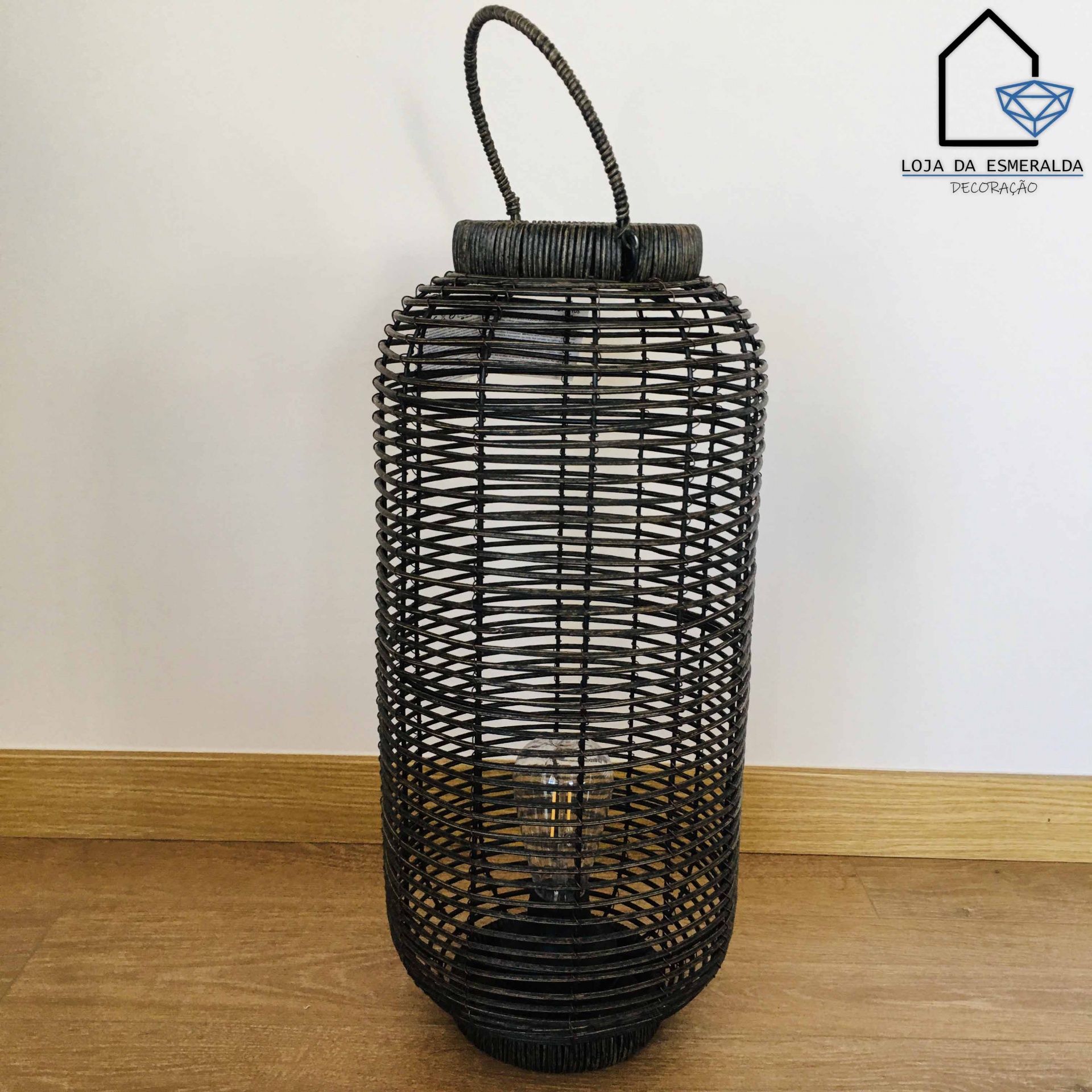 Lanterna decorativa preta de material trançado com alça, em chão de madeira clara