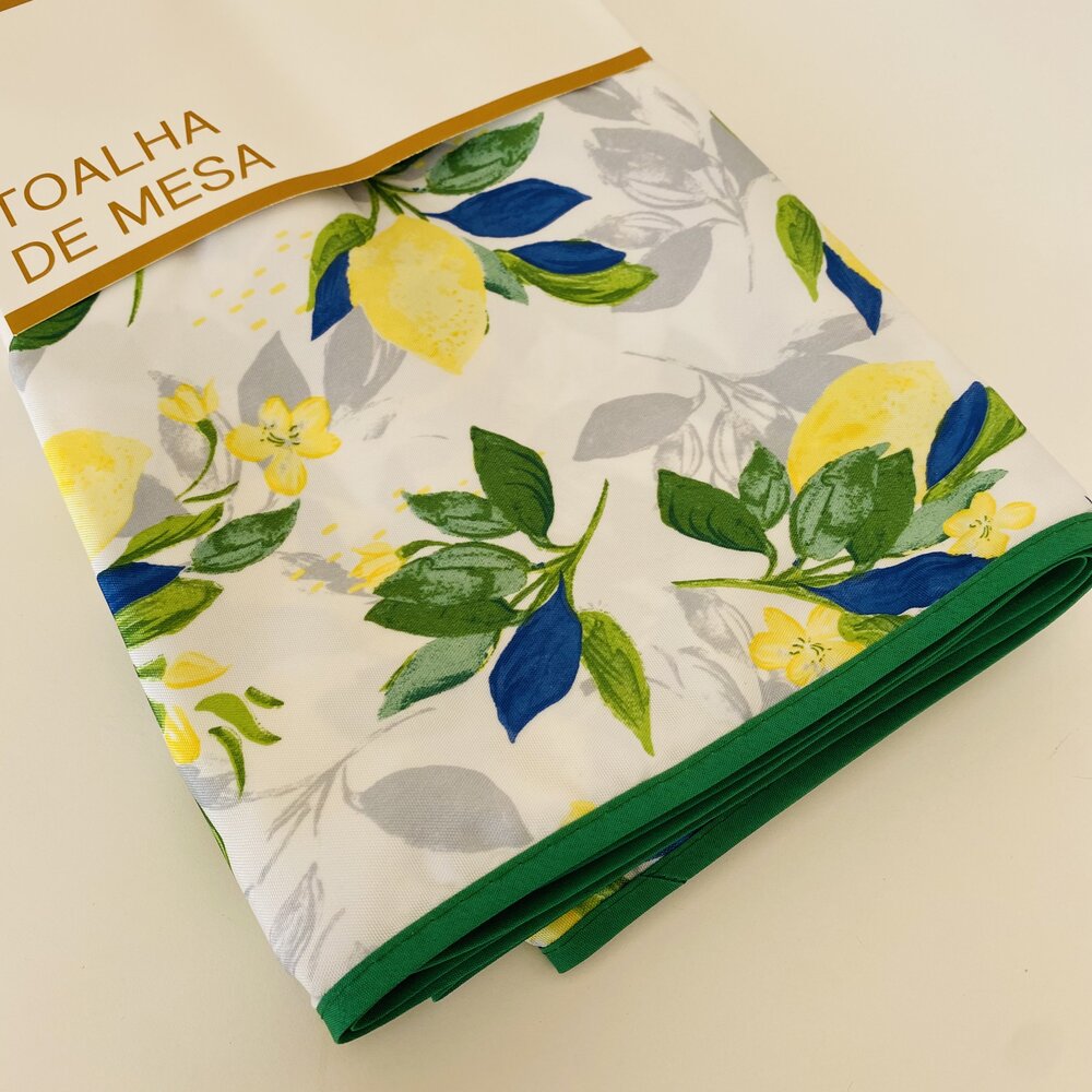 Toalha de mesa branca com padrão floral colorido e etiqueta com texto.