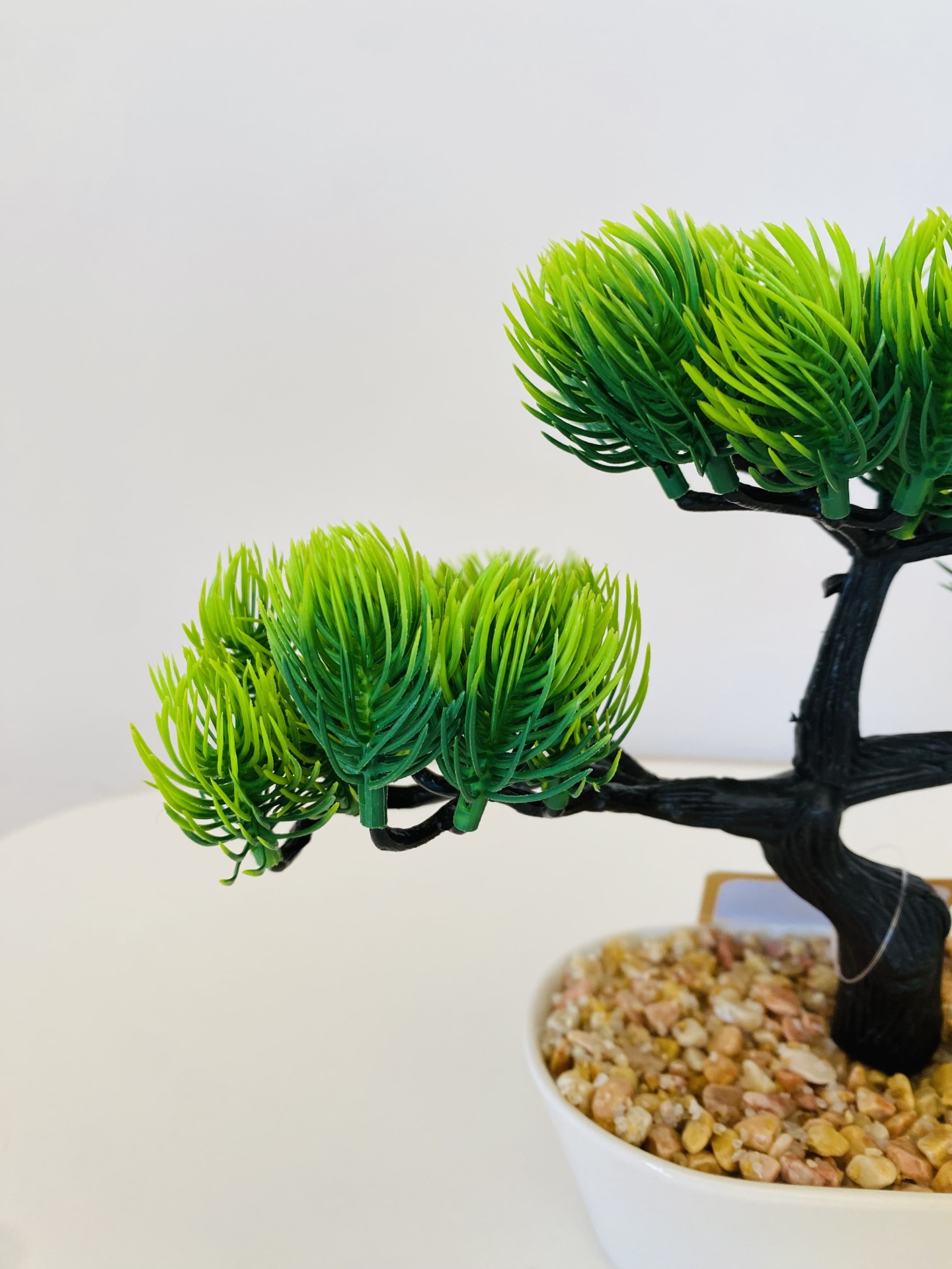Árvore artificial em vaso branco com pedras