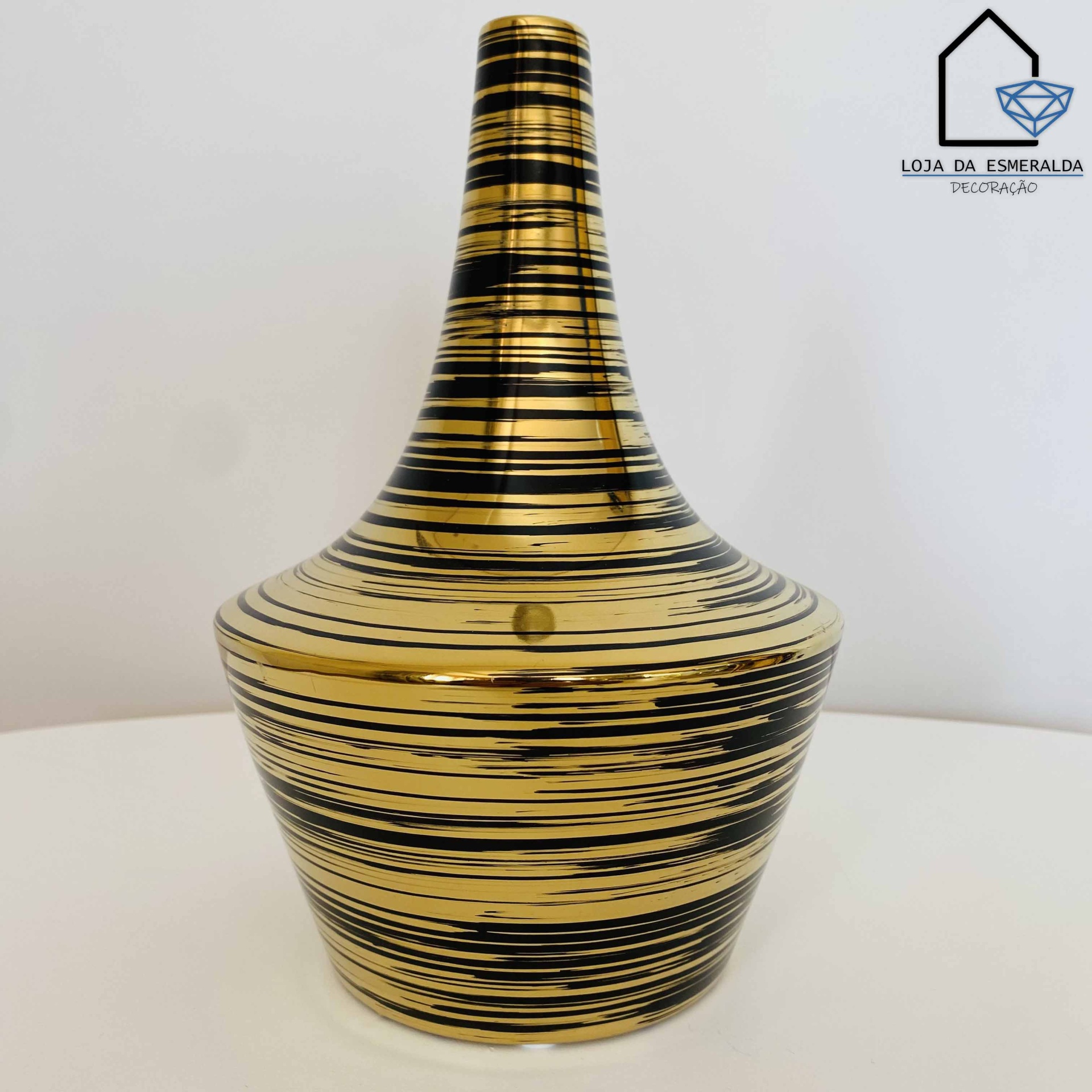 Vaso cerâmico dourado com riscas negras em fundo branco