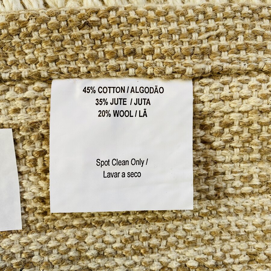 Etiqueta de tecido com composição e instruções de limpeza sobre tecido texturizado bege e castanho