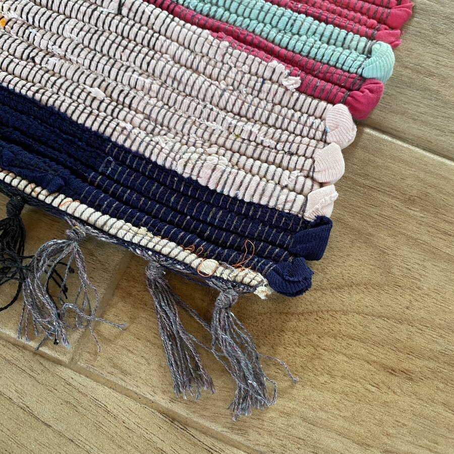 Tapetes tecidos coloridos com franjas sobre chão de madeira clara