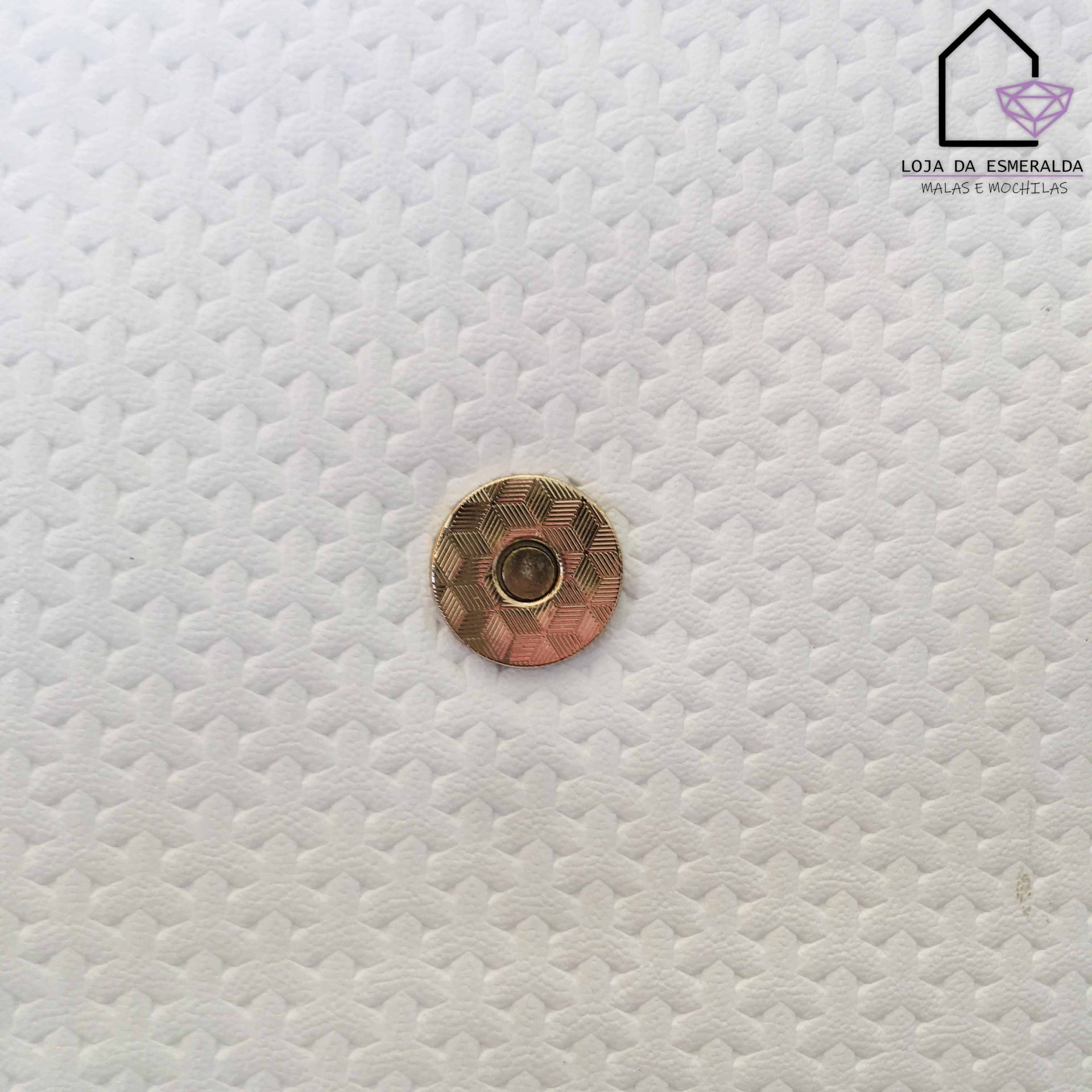 Fecho metálico dourado em tecido branco texturizado com logotipo Loja da Esmeralda no canto