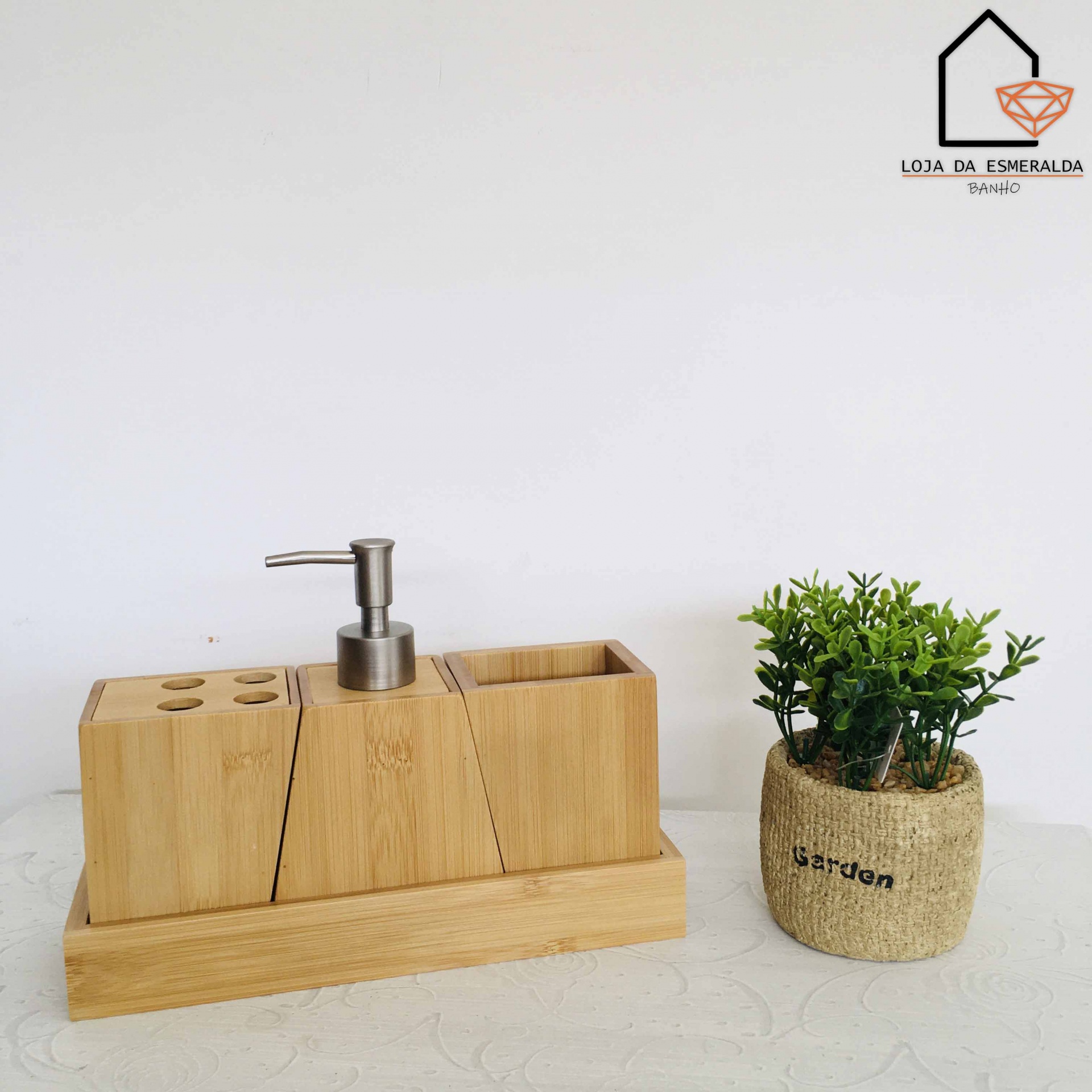 Conjunto de acessórios de casa de banho em madeira com doseador e suporte, ao lado de vaso decorativo com planta
