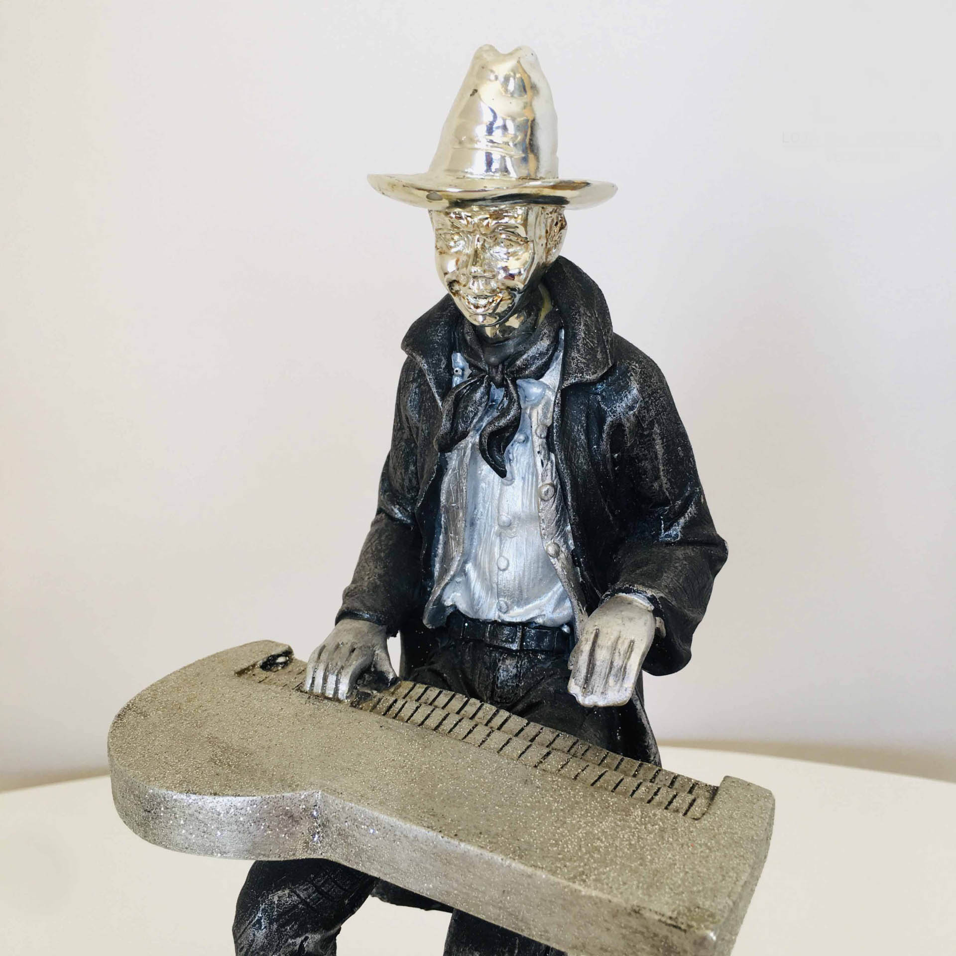 Figura decorativa de cowboy a tocar um instrumento prateado