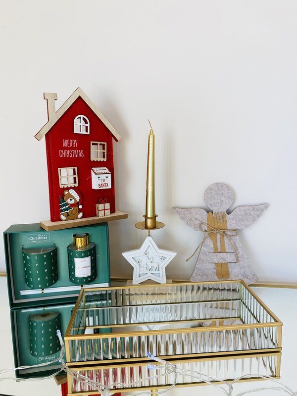 Decoração natalícia com casa vermelha, castiçal em forma de estrela, anjo de feltro, chávena e frasco verde e caixa espelhada dourada