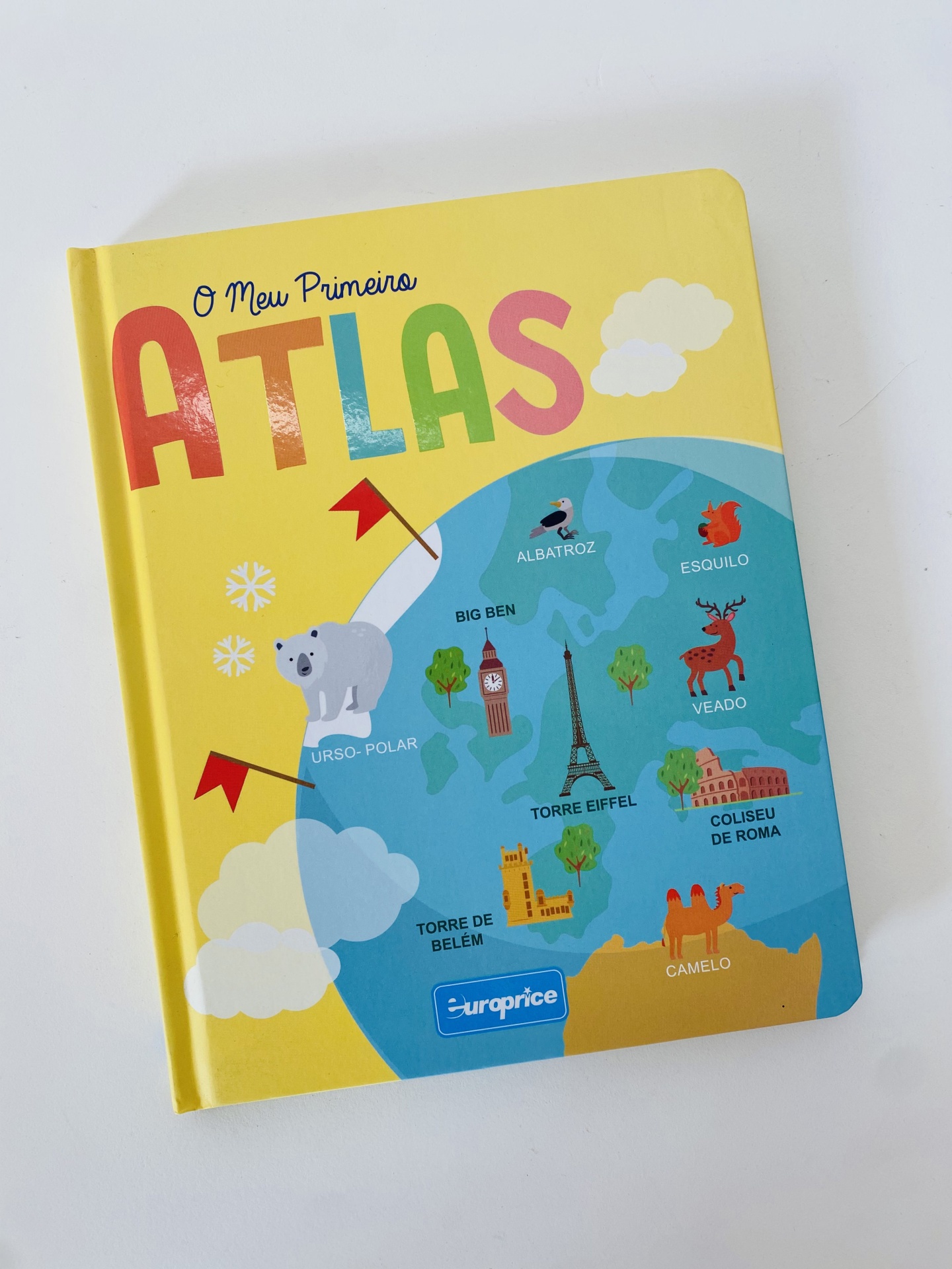 Livro infantil colorido com título 'O Meu Primeiro ATLAS' e ilustrações de animais e monumentos num mapa.