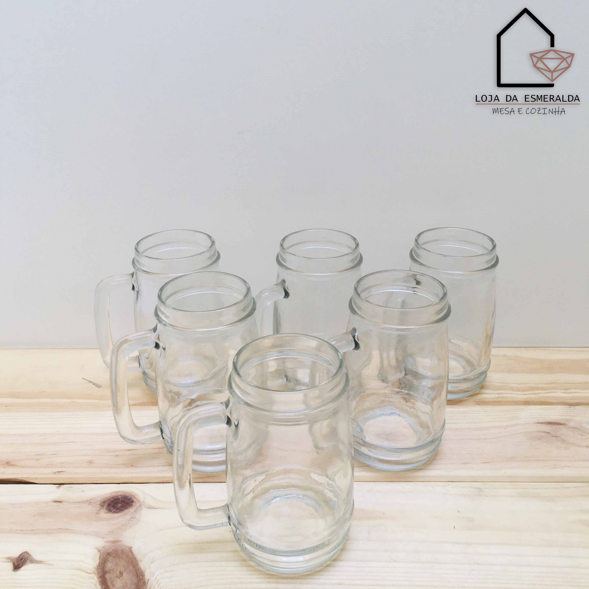 Seis canecas de vidro com pega sobre mesa de madeira clara
