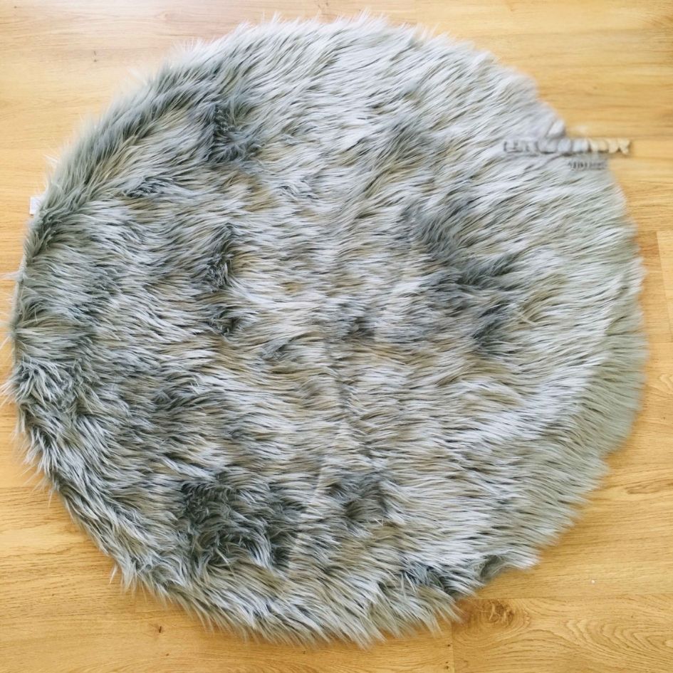 Tapete redondo cinzento de pêlo sintético sobre chão de madeira clara