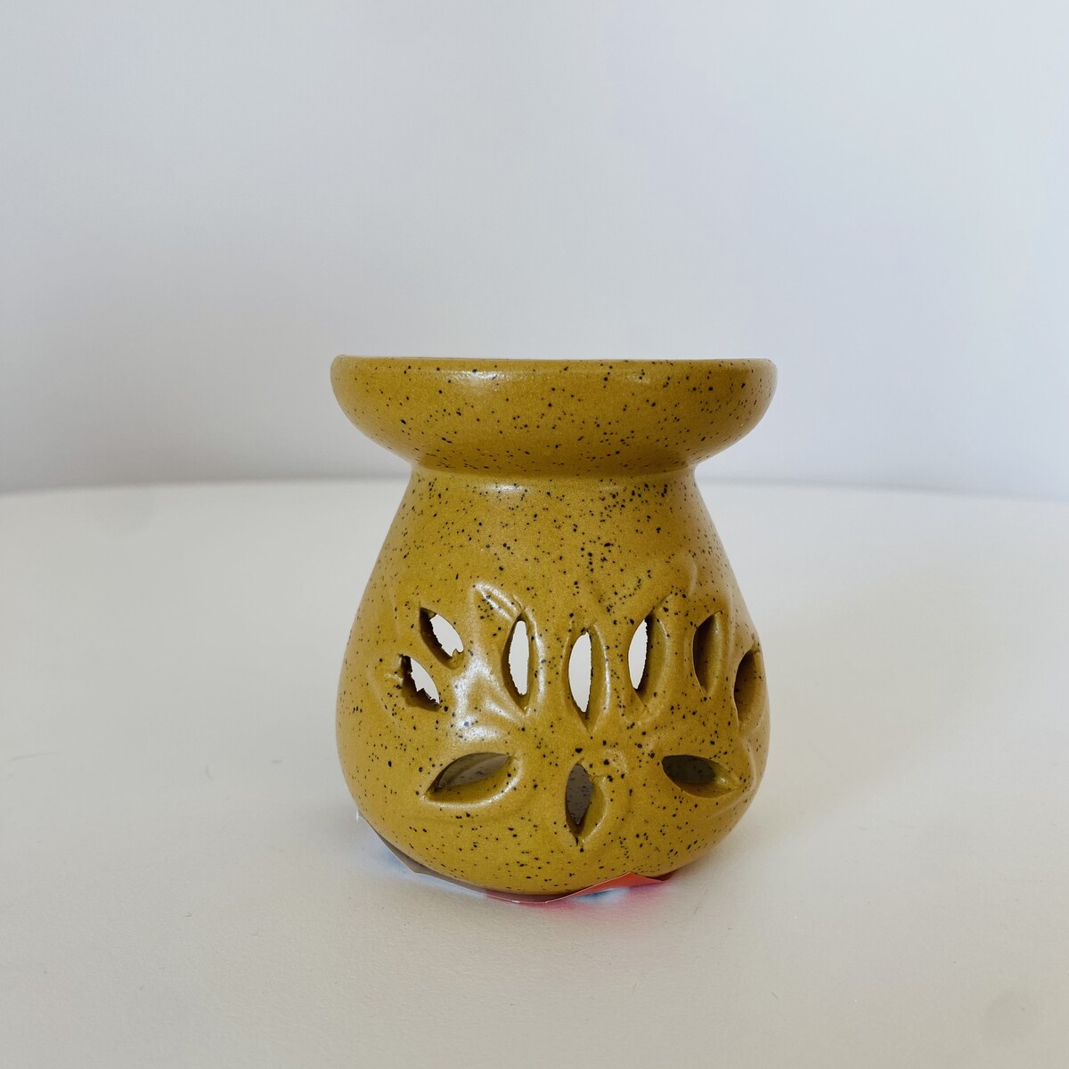 Recipiente de cerâmica amarelo com recortes em forma de folhas