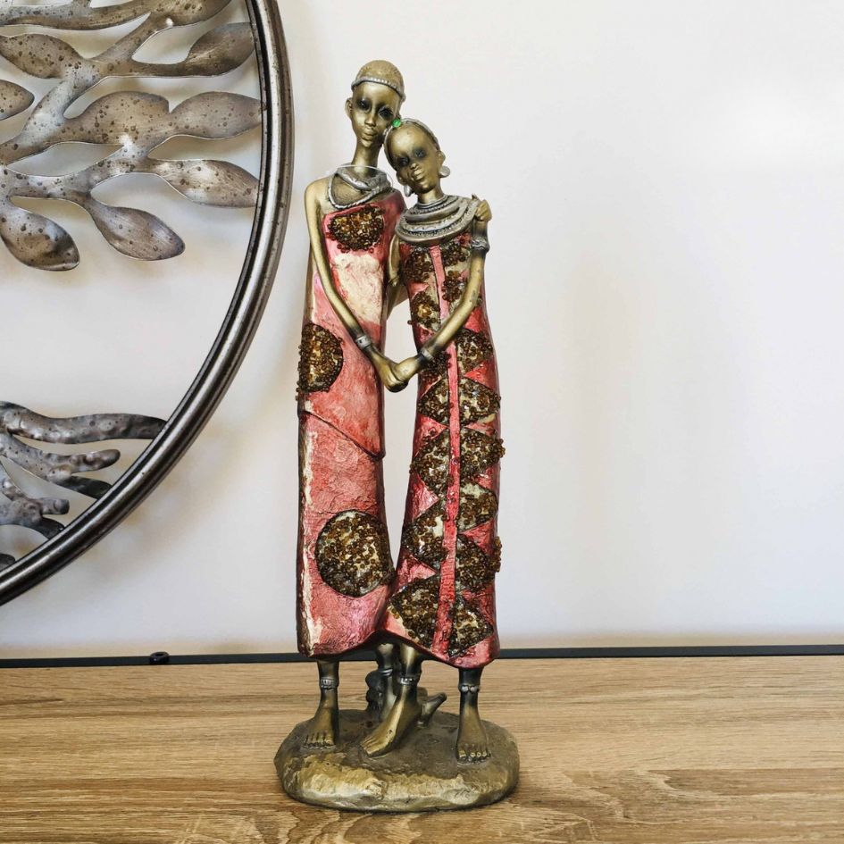 Estátua decorativa de duas figuras femininas em metal com vestidos cor de rosa e castanho