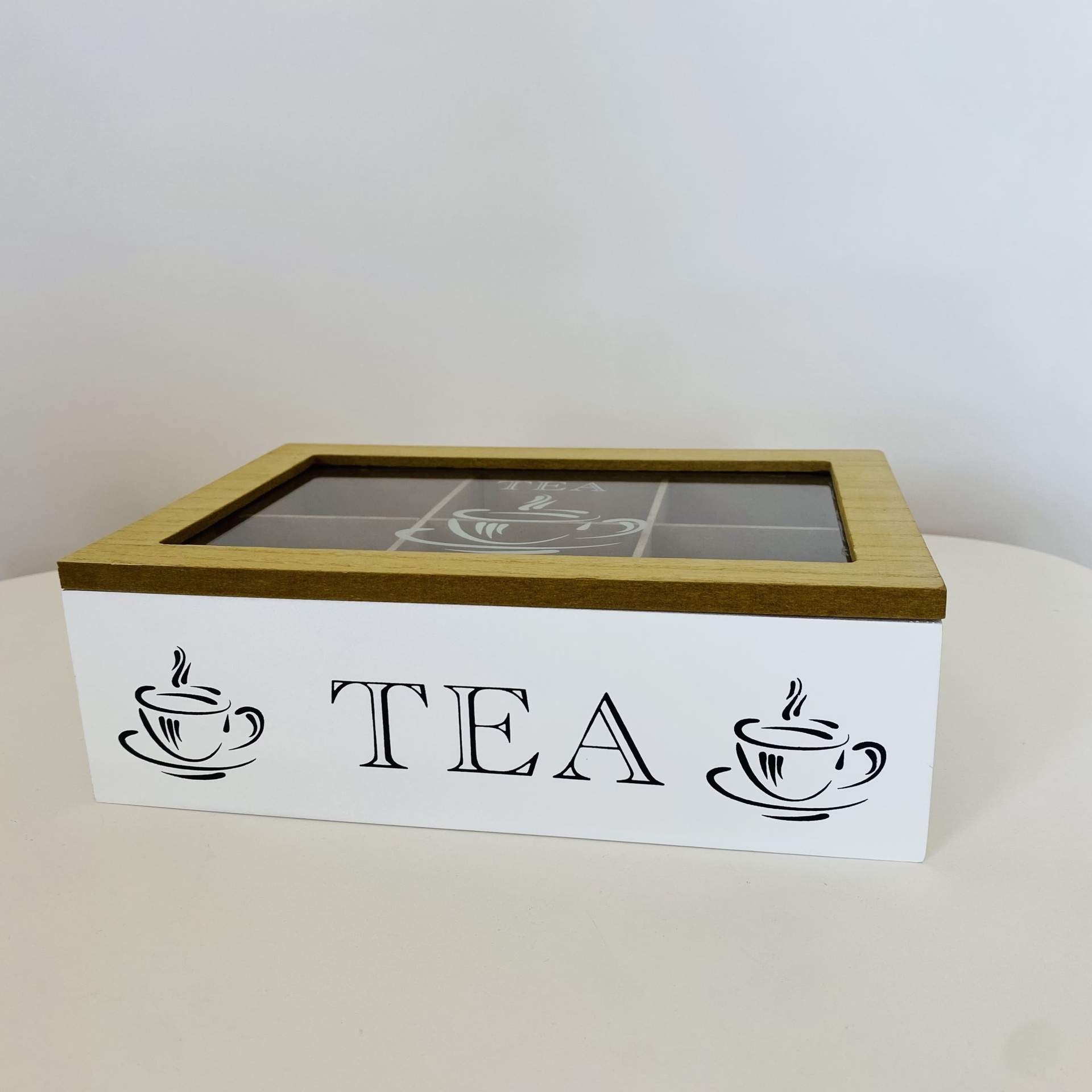 Caixa de chá em madeira com tampa de vidro e texto TEA