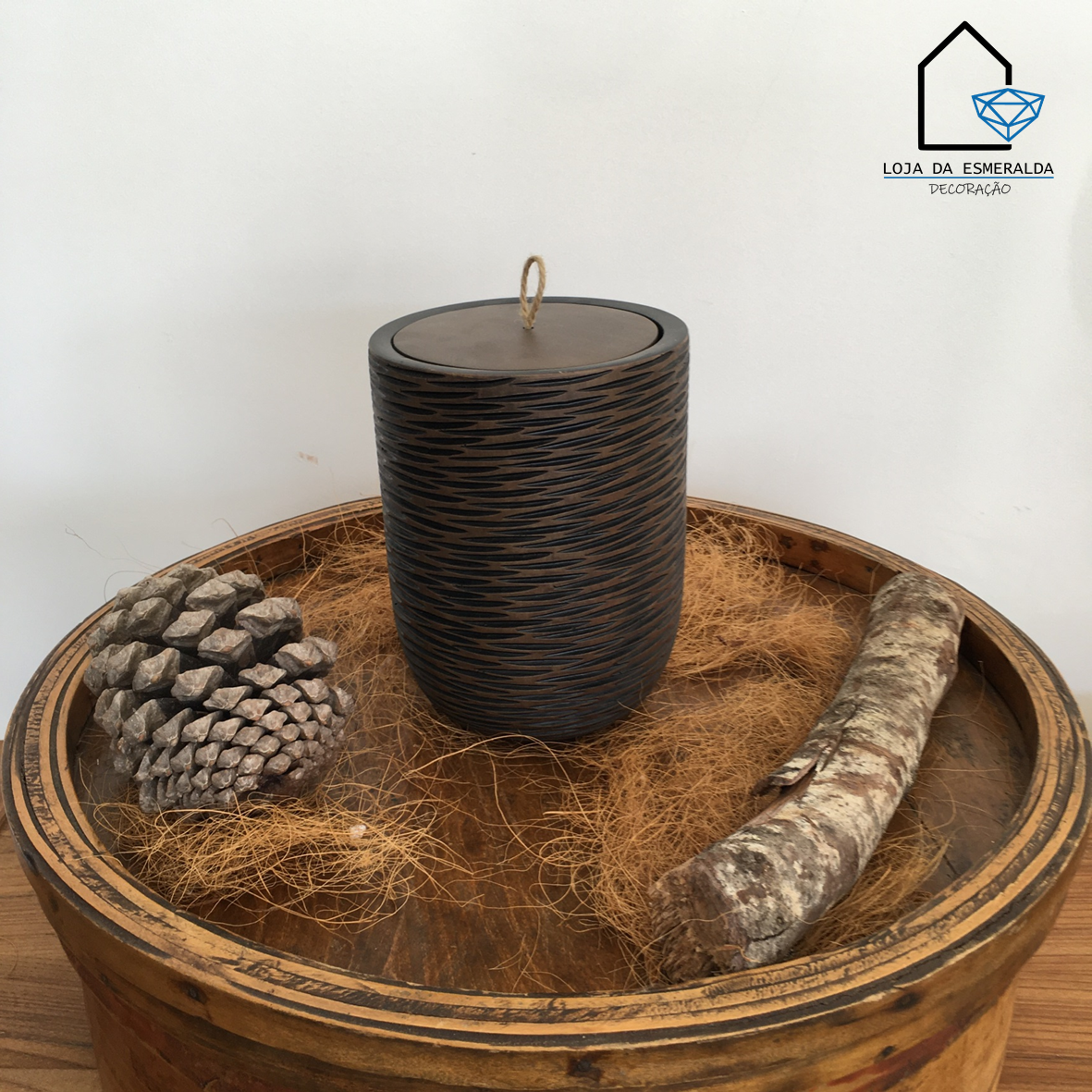 Pote decorativo preto e castanho com tampa em bandeja de madeira rústica com pinha e pedaço de madeira