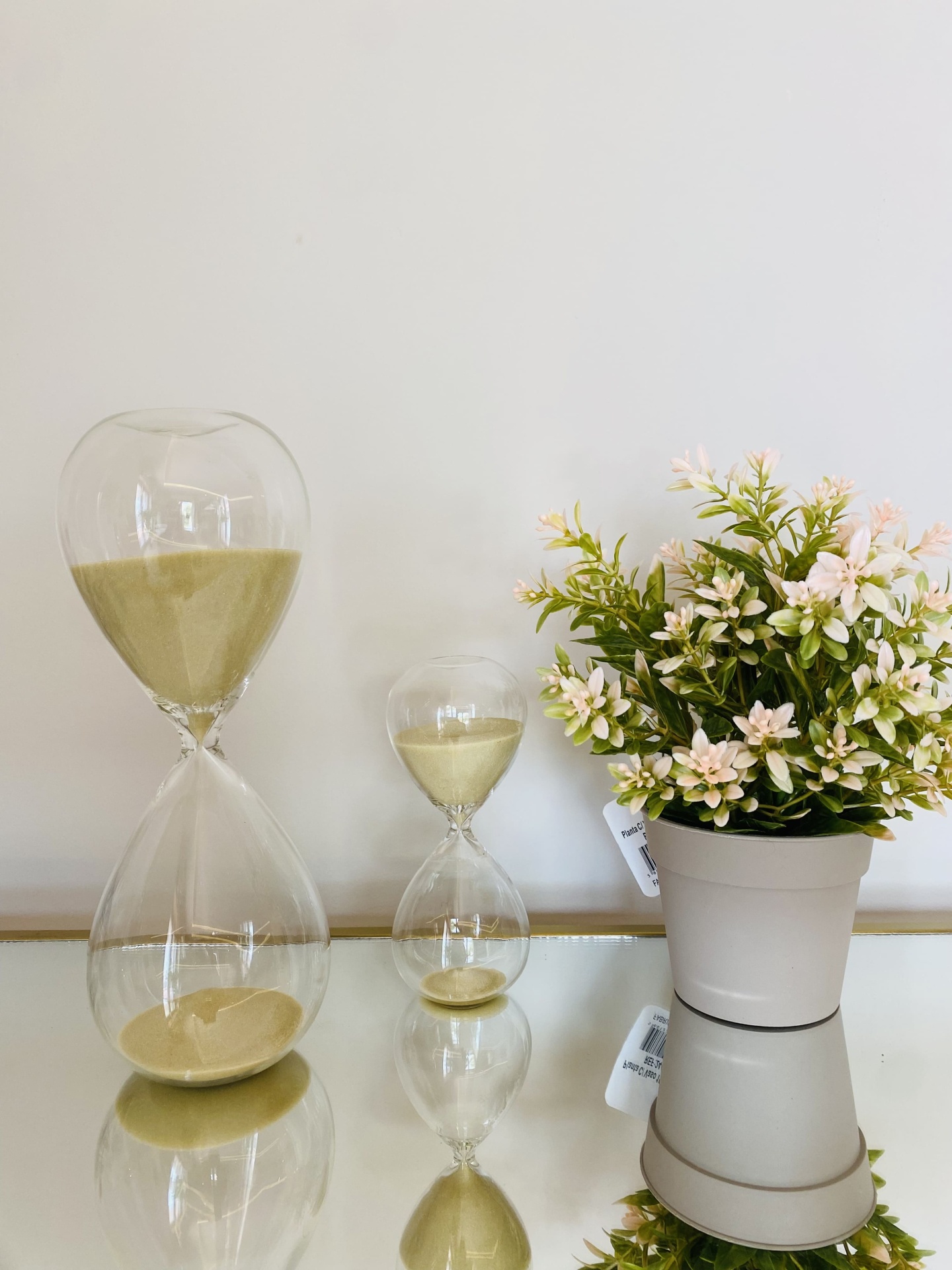 Ampulhetas de vidro com areia e vaso com planta artificial