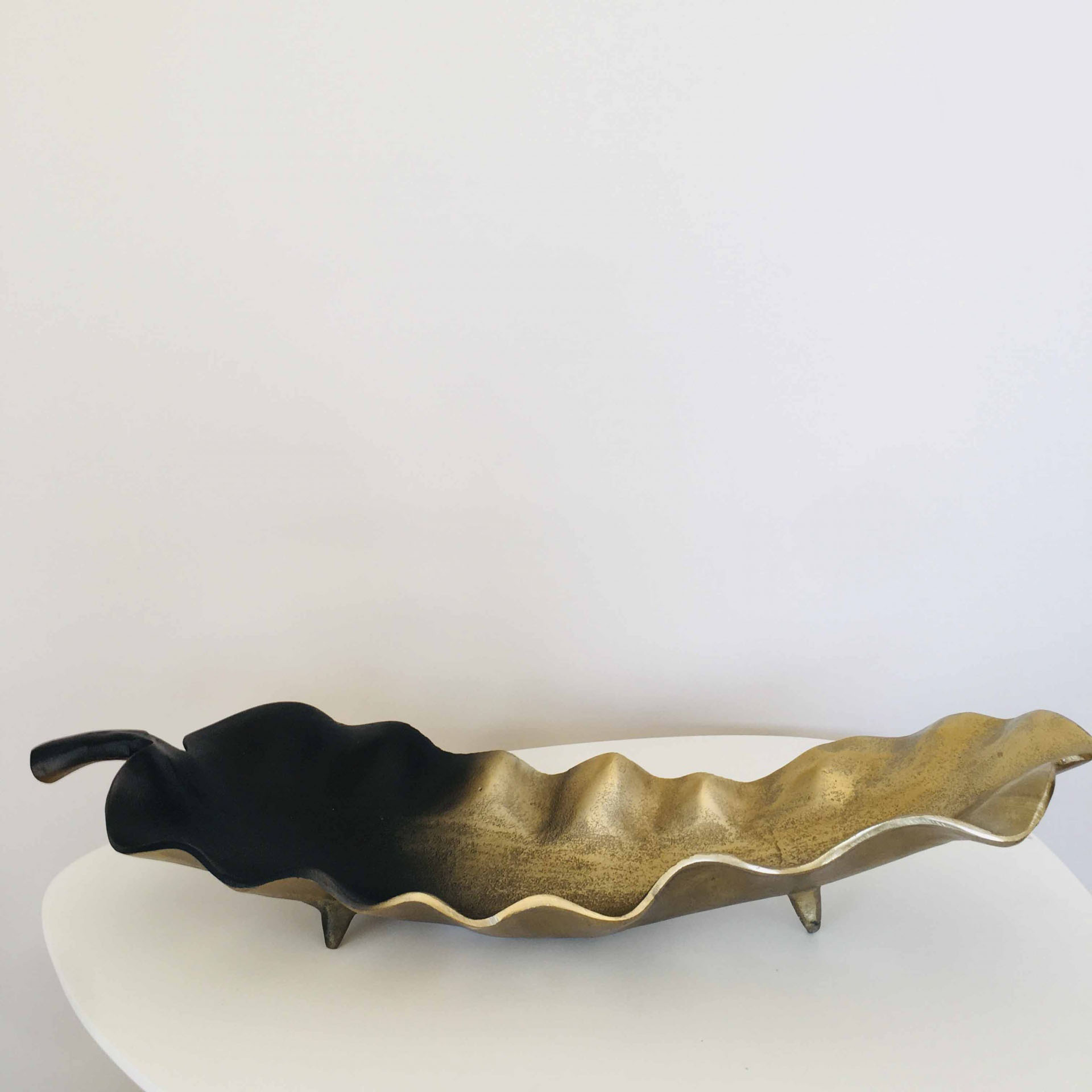 Prato decorativo metálico em forma de folha preto e dourado com textura ondulada