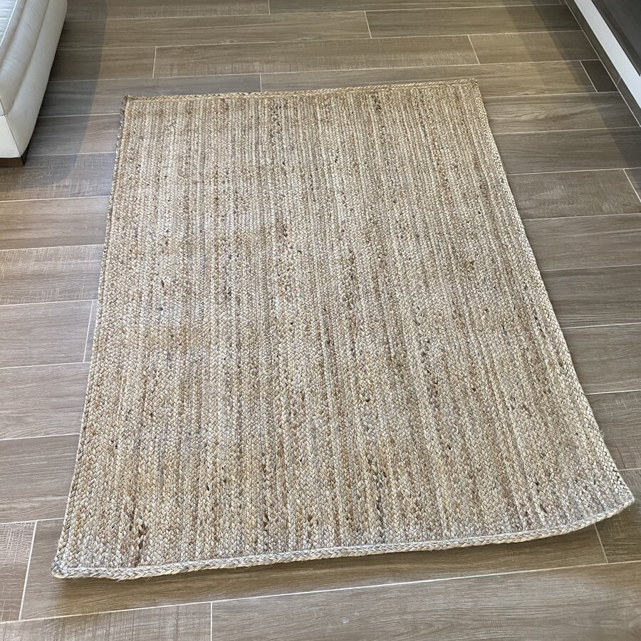 Tapete retangular bege com textura natural sobre chão de ladrilhos cinza e bege