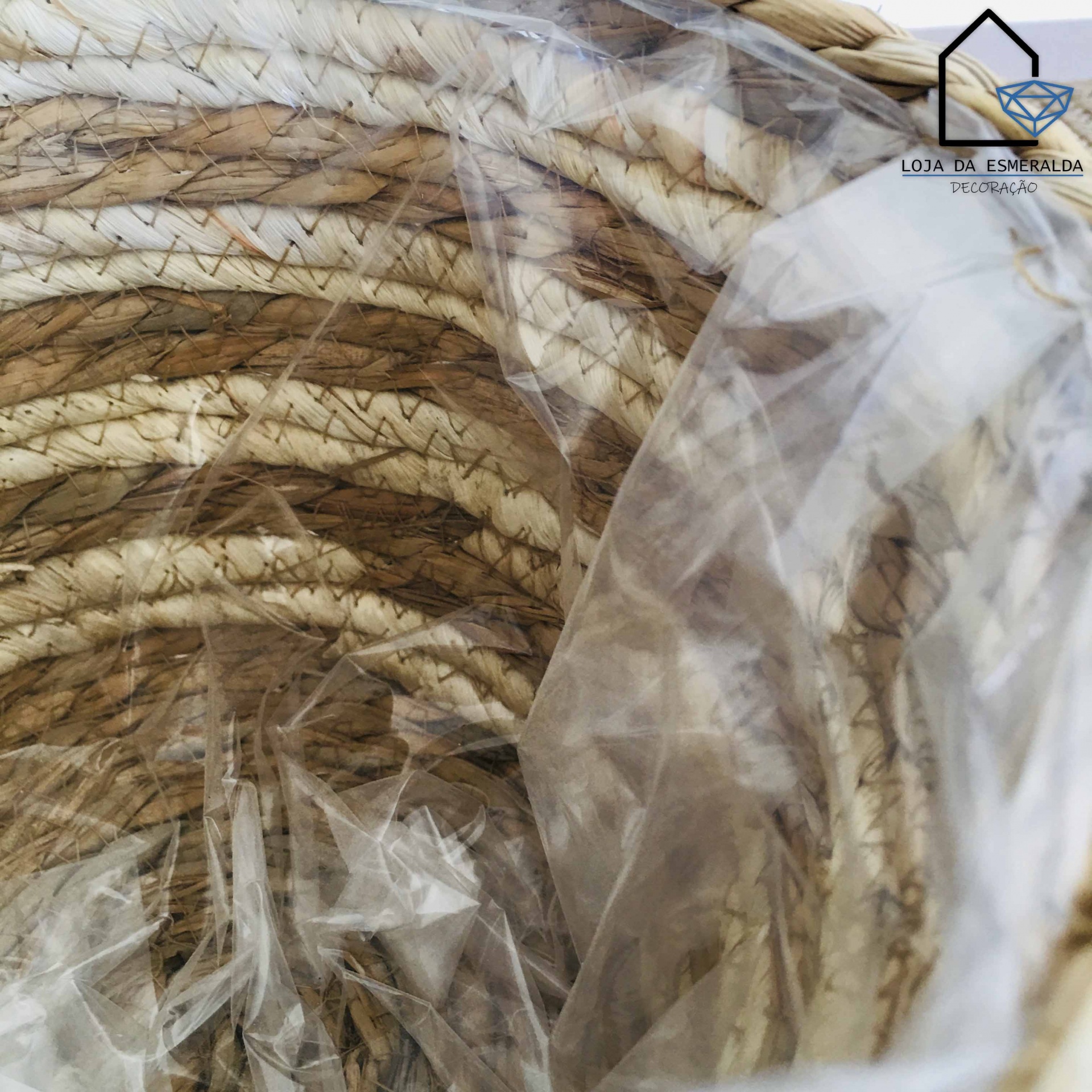 Cesto trançado em tons bege e castanho, coberto por plástico transparente