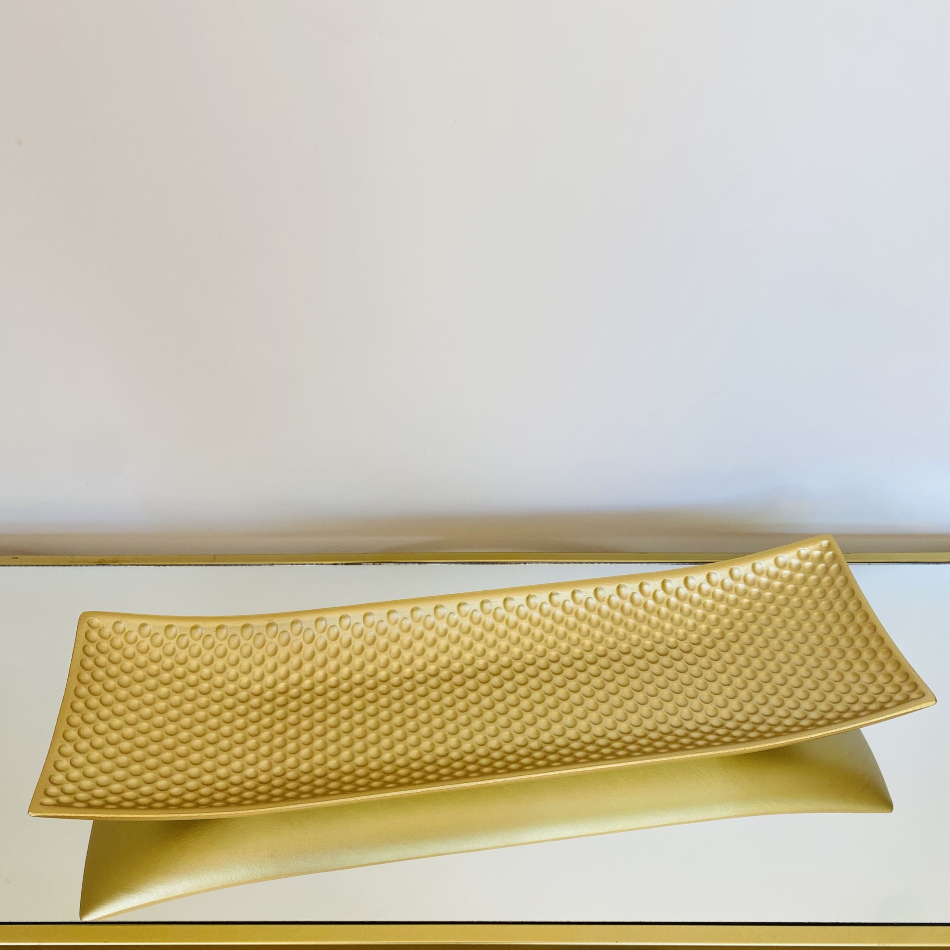 Prato decorativo retangular dourado com textura bolha sobre espelho dourado