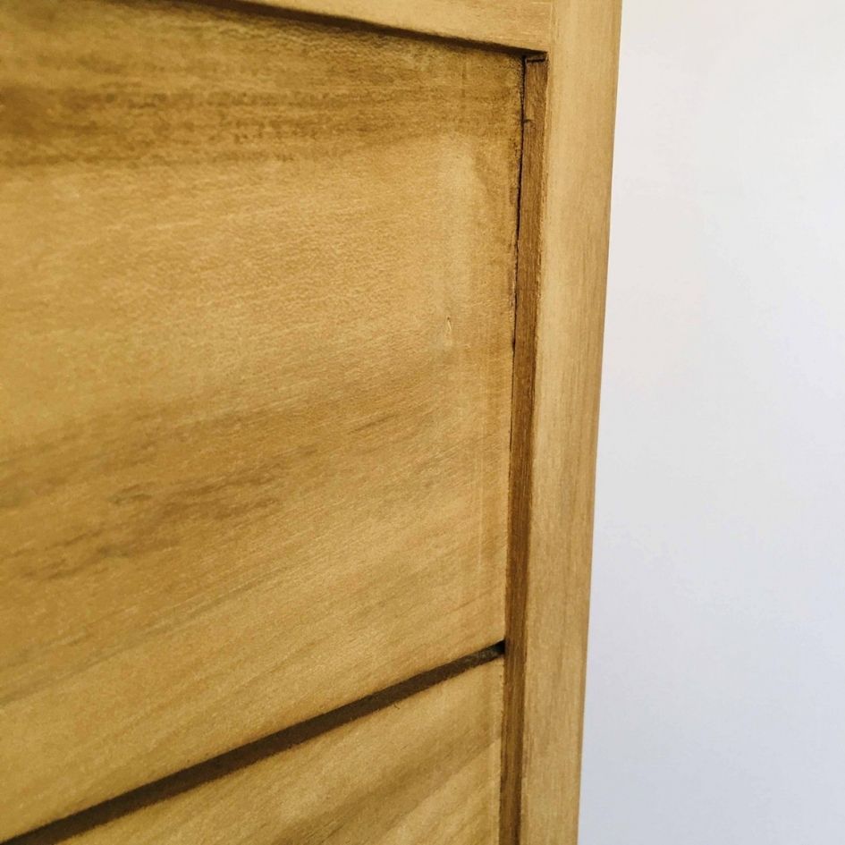 Detalhe de móvel em madeira clara com textura e junções visíveis junto a parede branca