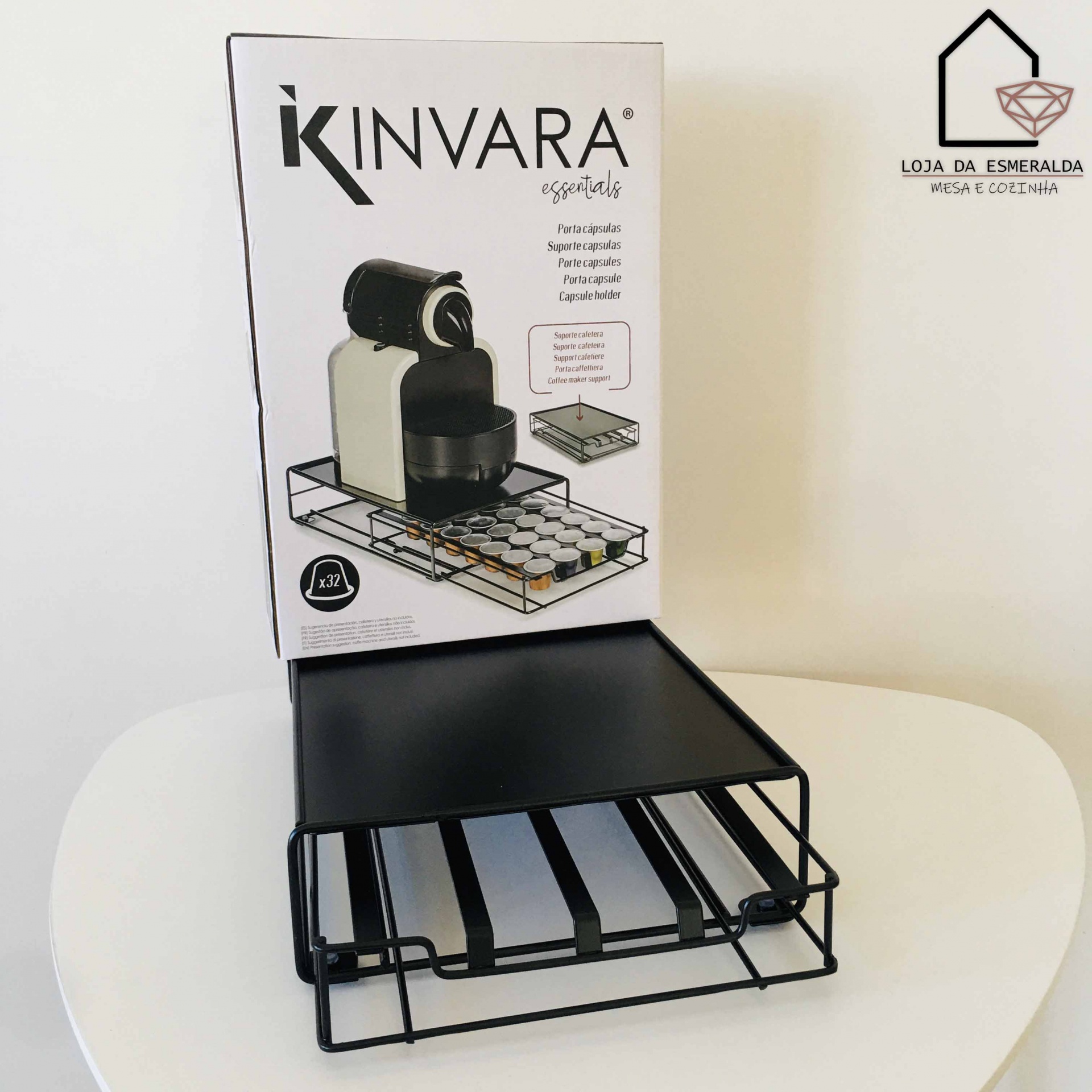 Suporte preto para máquina de café com gaveta para cápsulas em caixa sobre mesa branca.